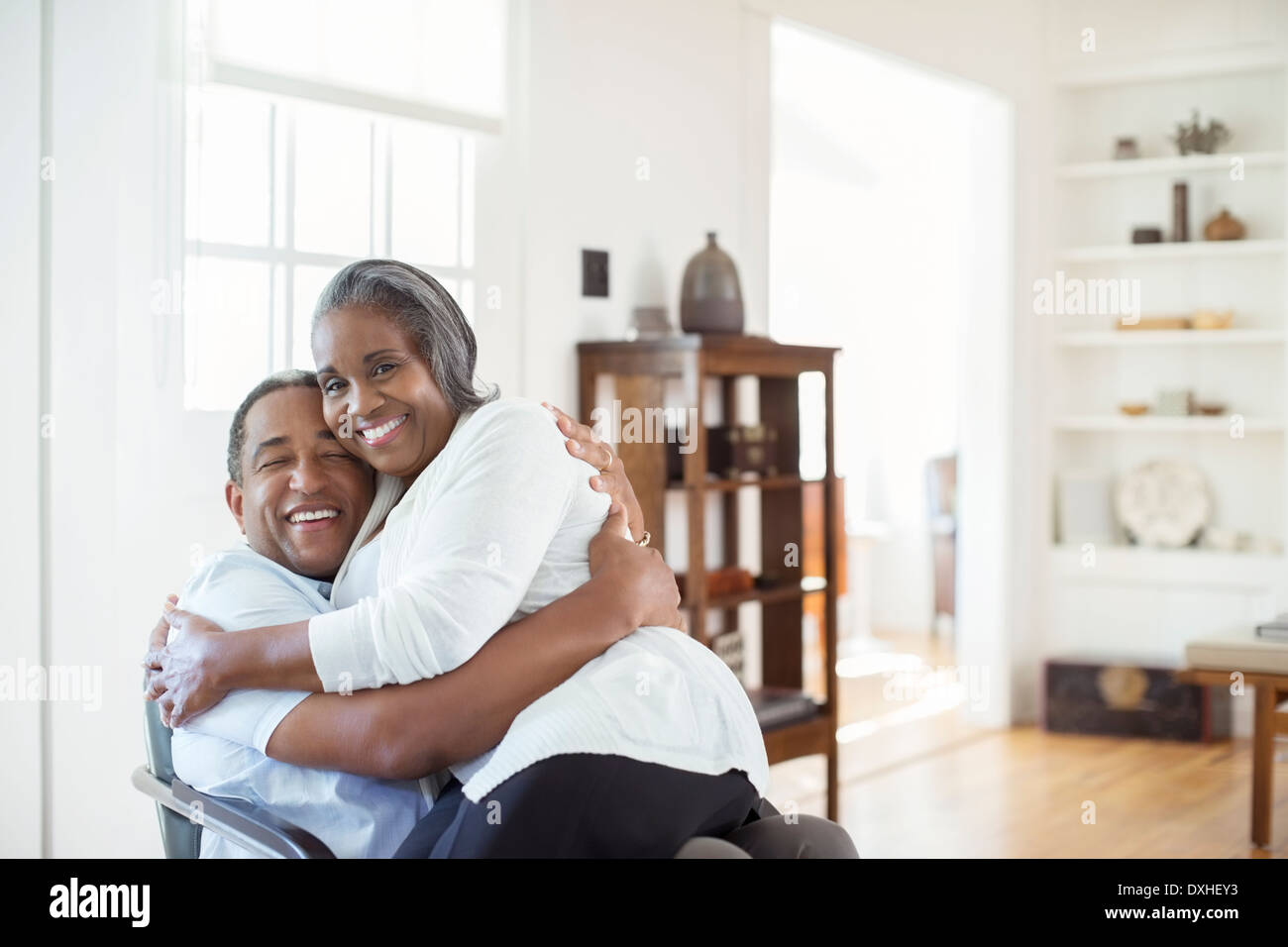 Happy senior couple hugging in living room Stock Photo