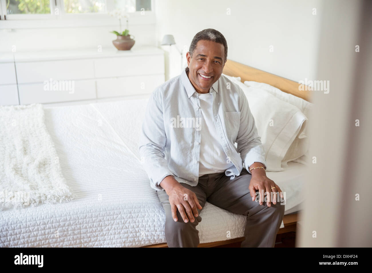 Portrait of smiling senior man sitting on bed Stock Photo