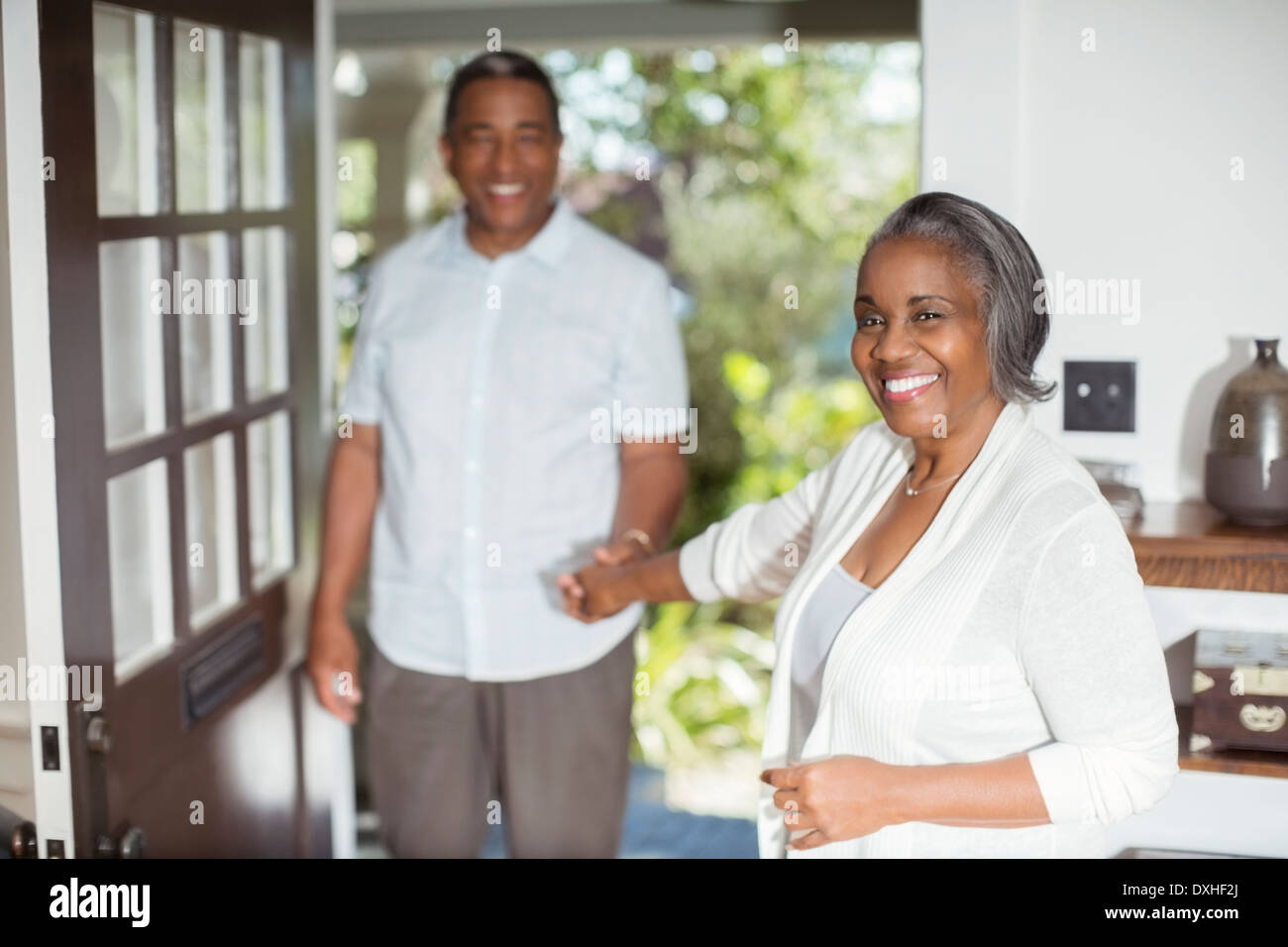 Portrait of smiling senior couple holding hands in doorway Stock Photo