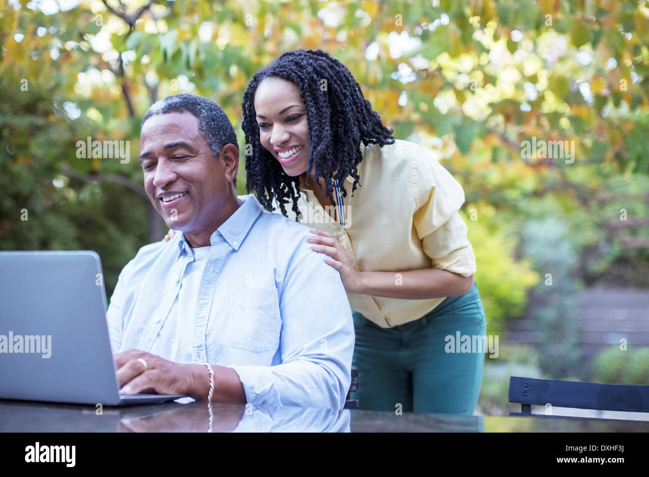 Father and daughter using laptop at patio table Stock Photo