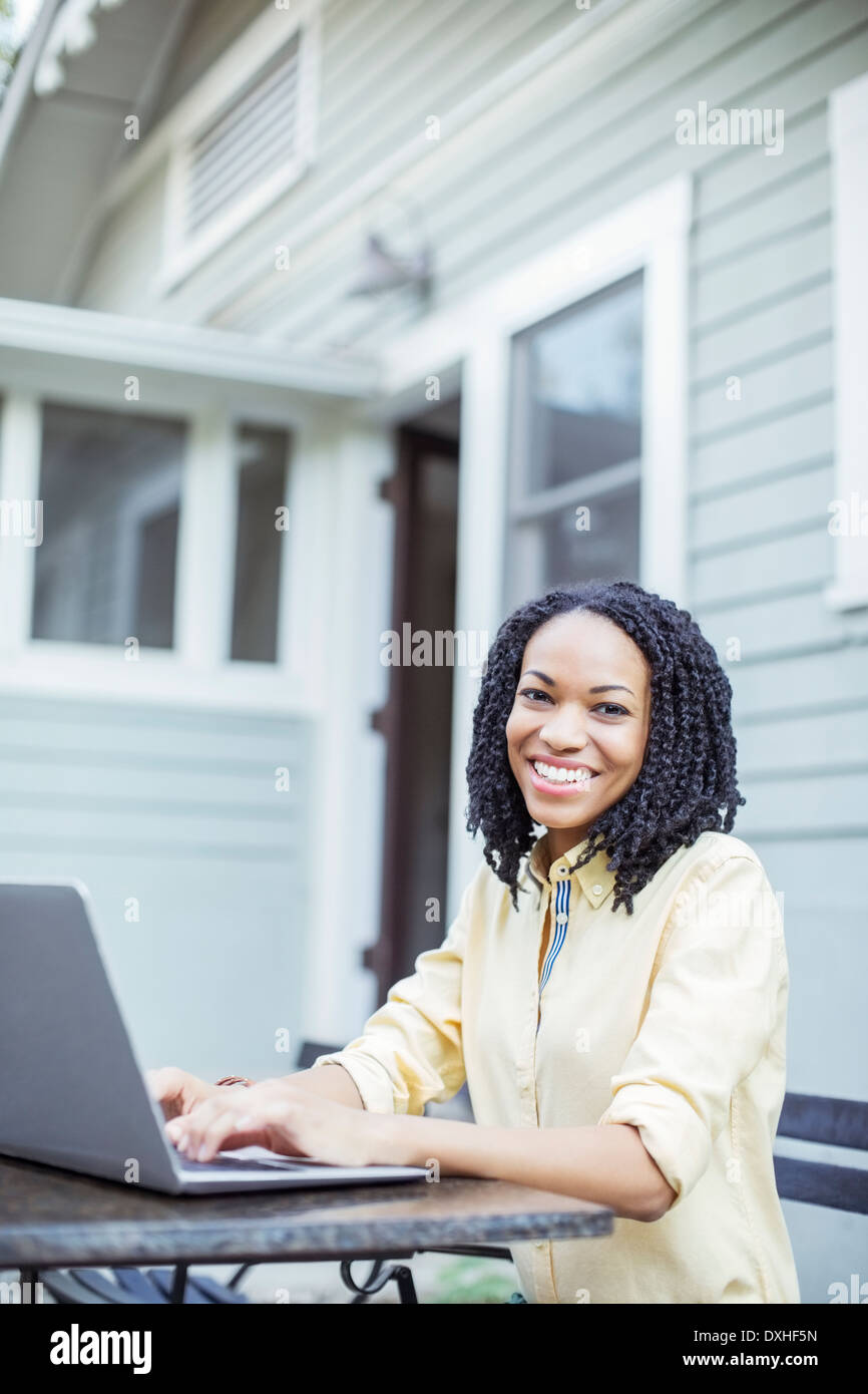 Portrait of smiling woman using laptop at patio table Stock Photo - Alamy