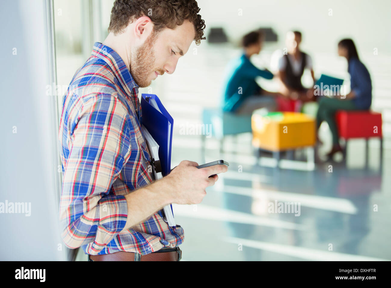 Businessman checking cell phone outside meeting Stock Photo