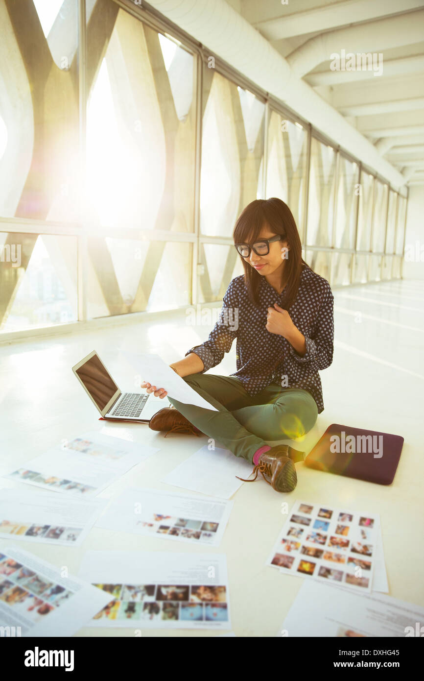 Creative businesswoman looking at photograph proofs on office floor Stock Photo