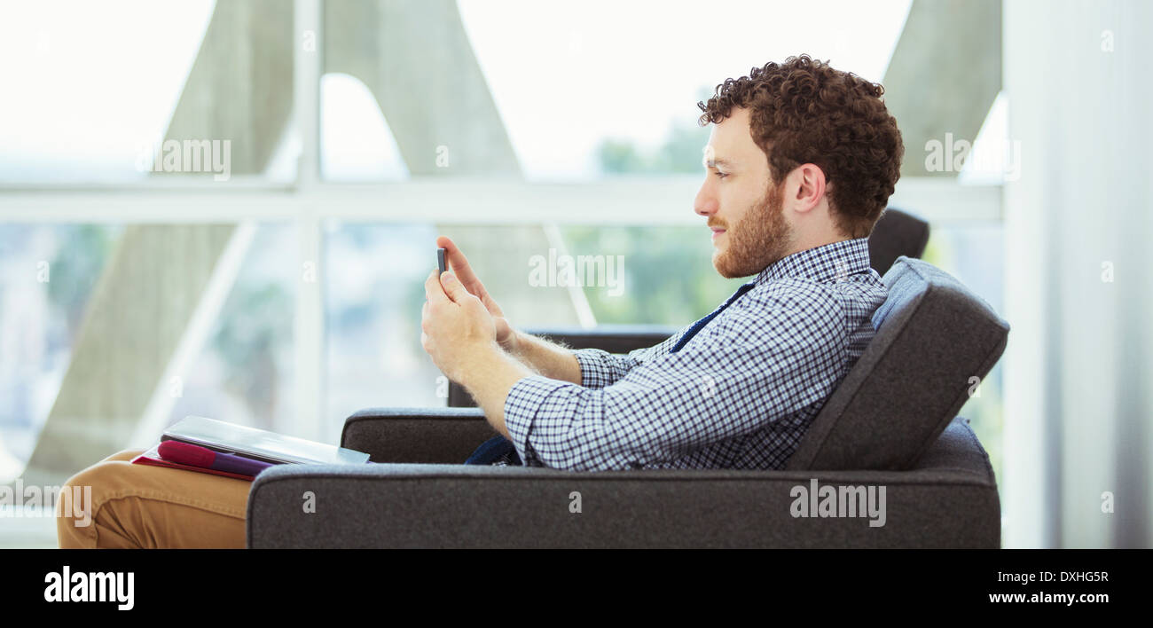 Businessman using cell phone in lobby Stock Photo
