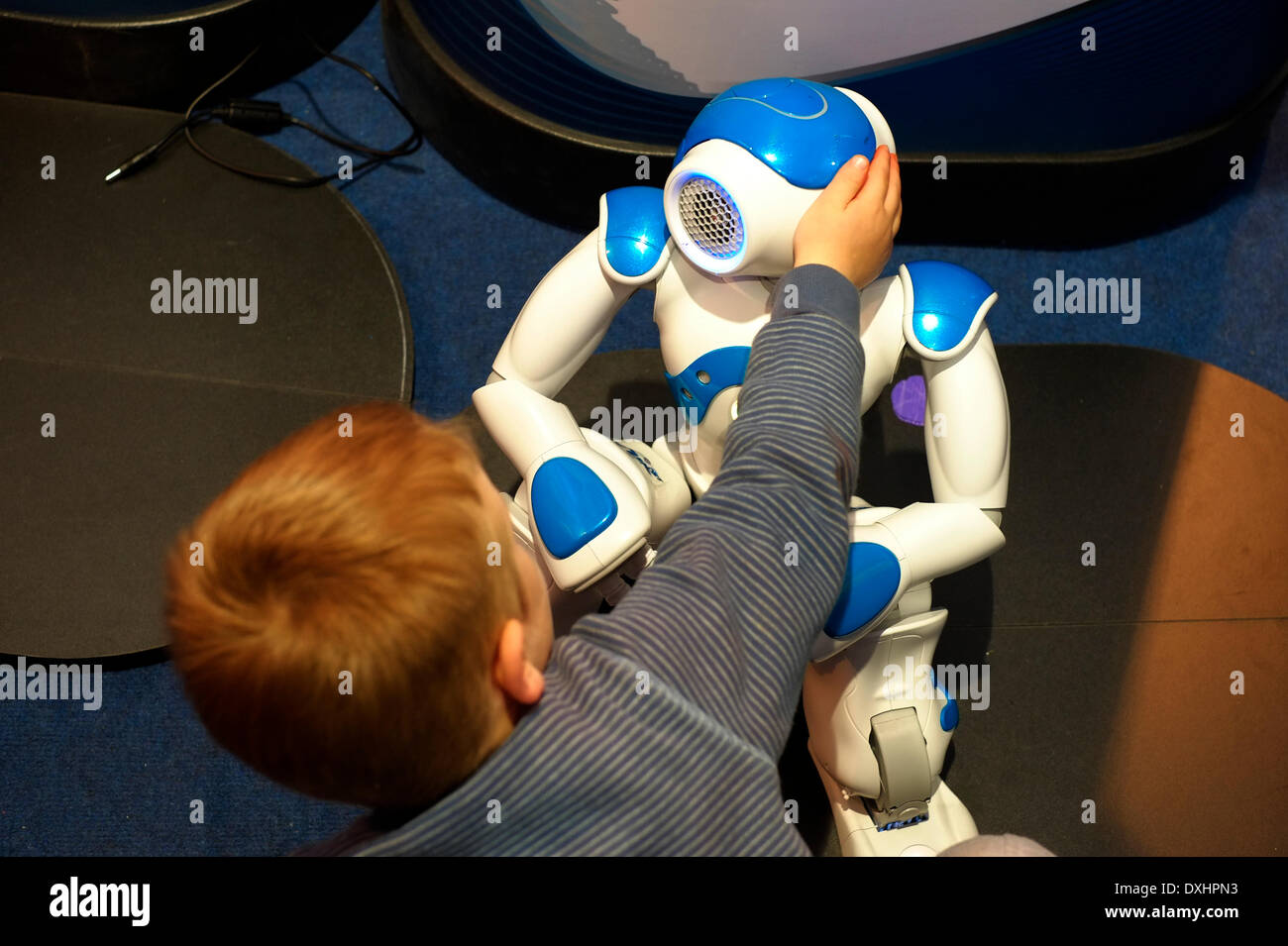 A young Israeli boy interact with a robot at a Science exhibition in Rabin Square during National Science Day in Tel Aviv on 26 March 2014. University campuses and museums around the country hold special events during Science day. The Tel Aviv municipality, turn its main  Square in the center of the city into the site of a giant science fair. Stock Photo