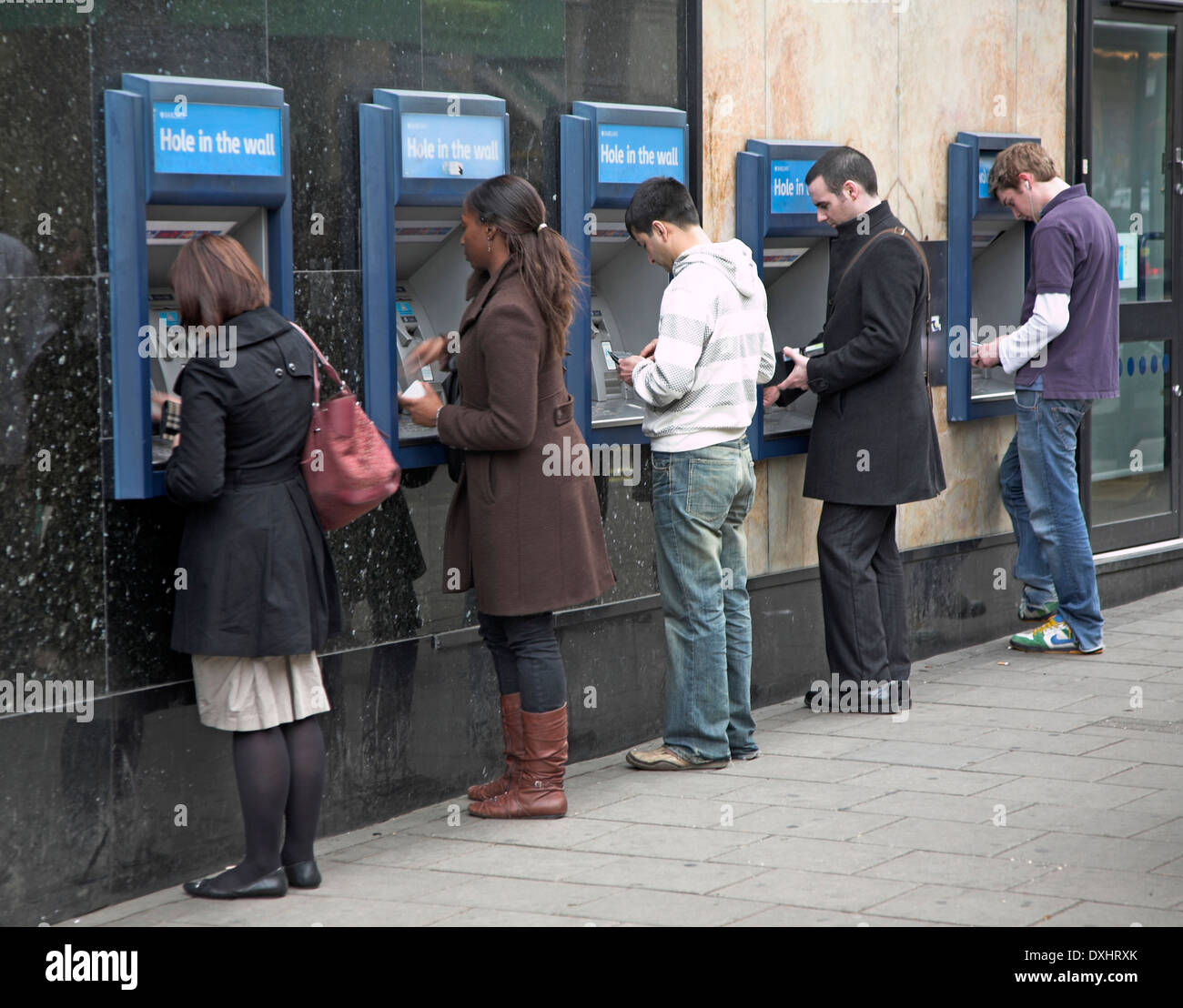 Line of five people at cash point machines, London, England Stock Photo