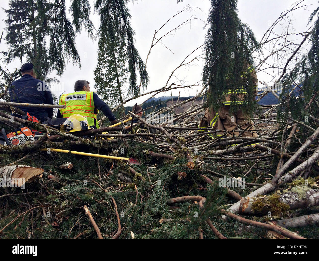 Rescue workers take a break during efforts to locate victims of a massive landslide that blocked the Stillaguamish River burying State Route 530 and causing a massive mudslide killing at least fourteen people and destroying a small riverside village in northwestern Washington state March 22, 2014 in Oso, Washington. Officials report that 176 people are still missing and feared dead. Stock Photo