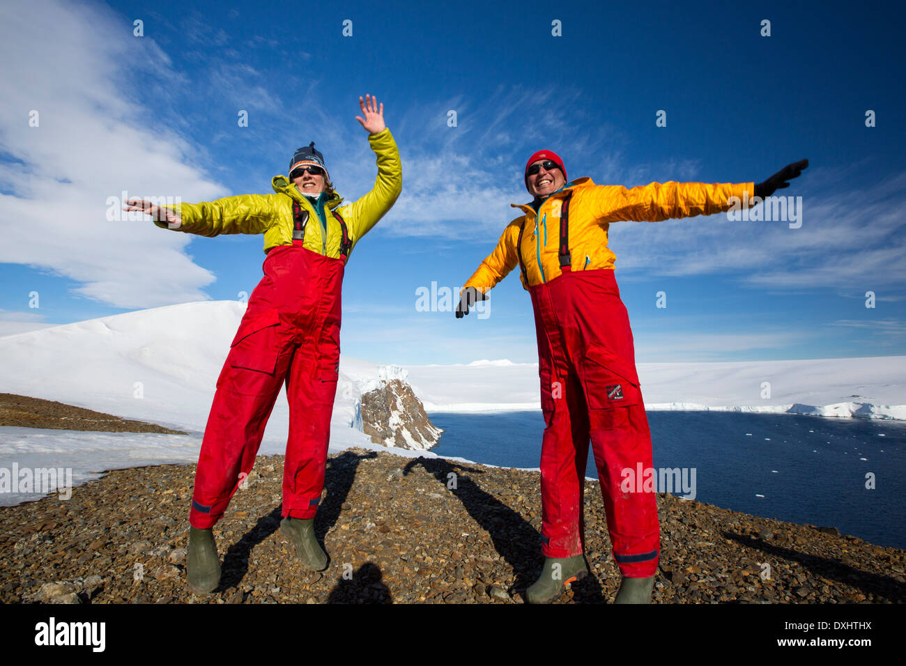 A man and woman jumping for joy from an expedition cruise on Joinville Island just off the Antarctic Peninsular. Stock Photo