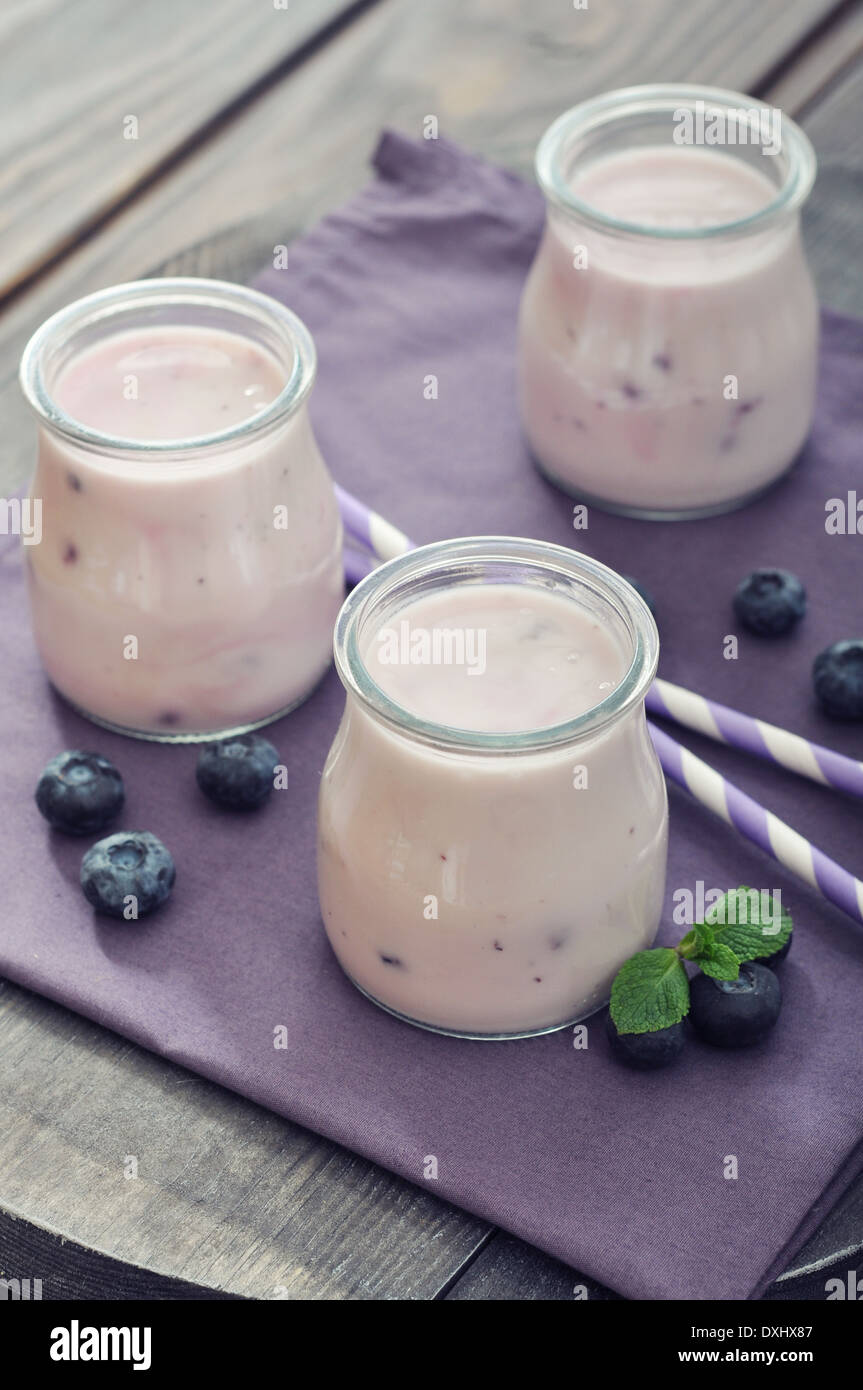 Yogurt with ripe fresh blueberry in jars on wooden background  Stock Photo