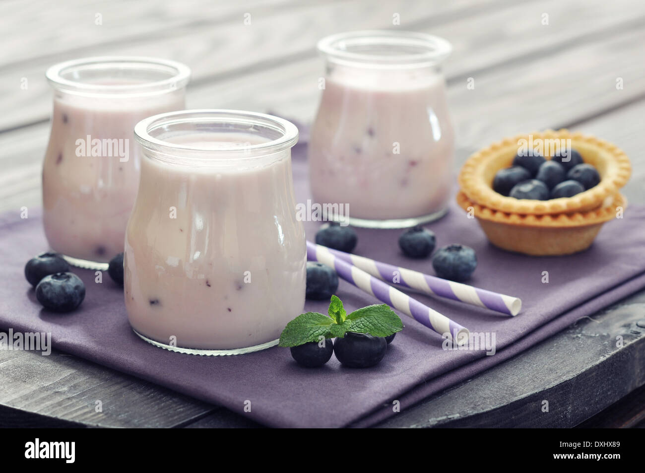 Yogurt with ripe fresh blueberry in jars on wooden background Stock Photo