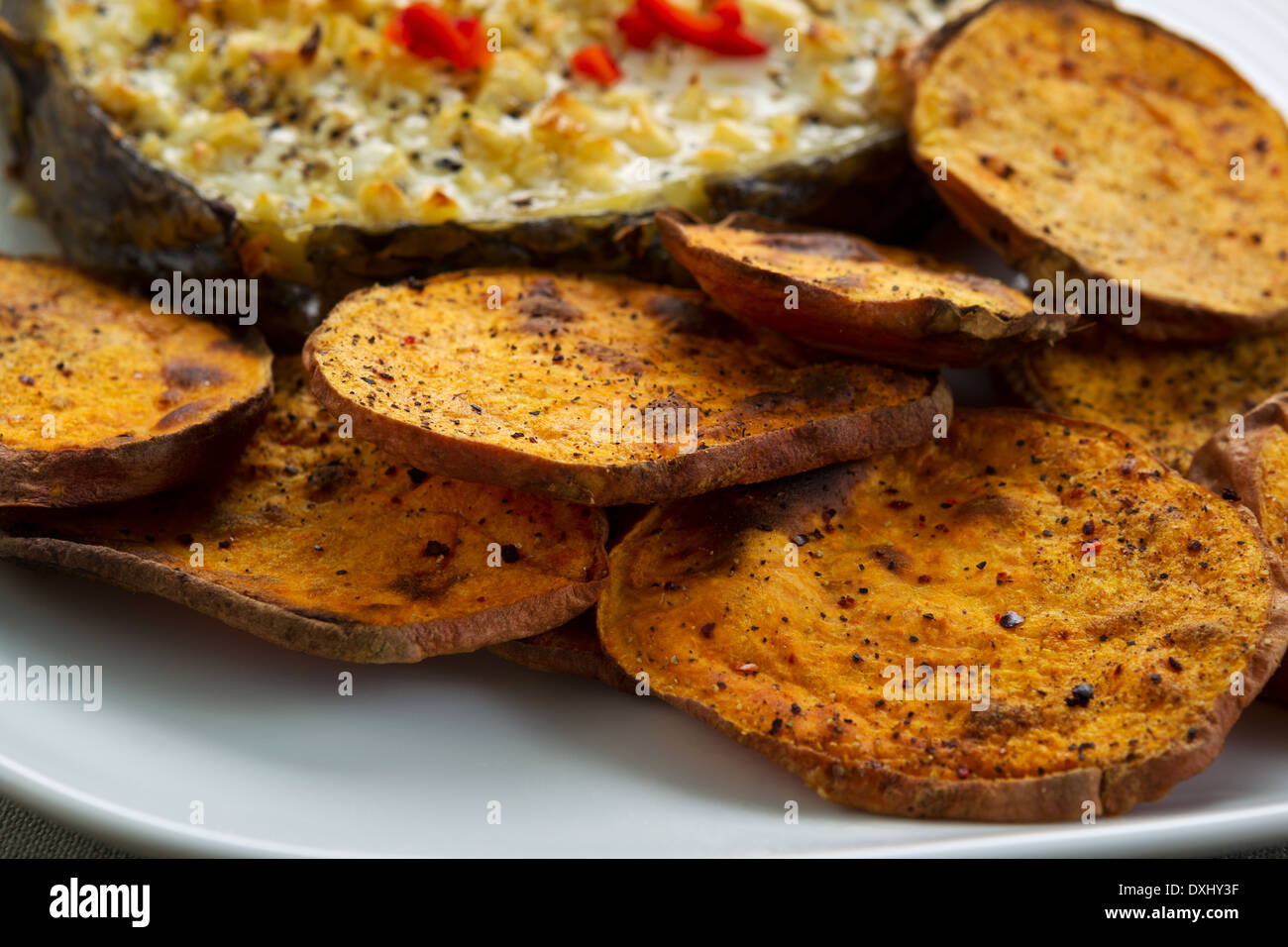 Horizontal closeup photo of baked yam slices and fish on white plate Stock Photo