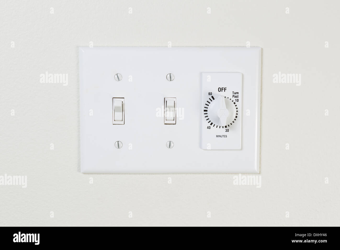 Horizontal photo of bathroom fan and light switches with timer on wall Stock Photo