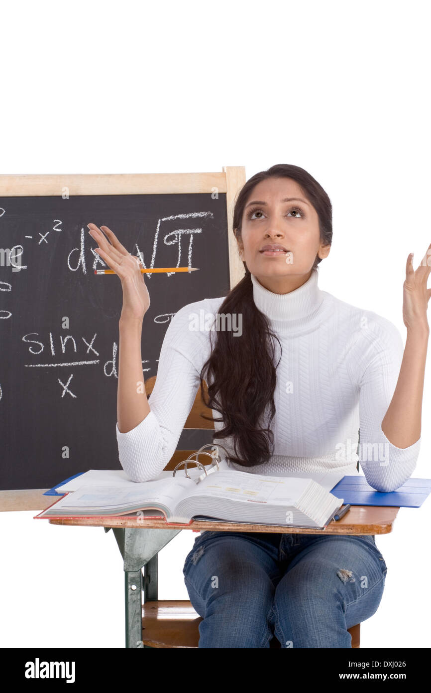 High school college ethnic Indian female student sitting by desk at math class. Blackboard with advanced mathematical formulas Stock Photo