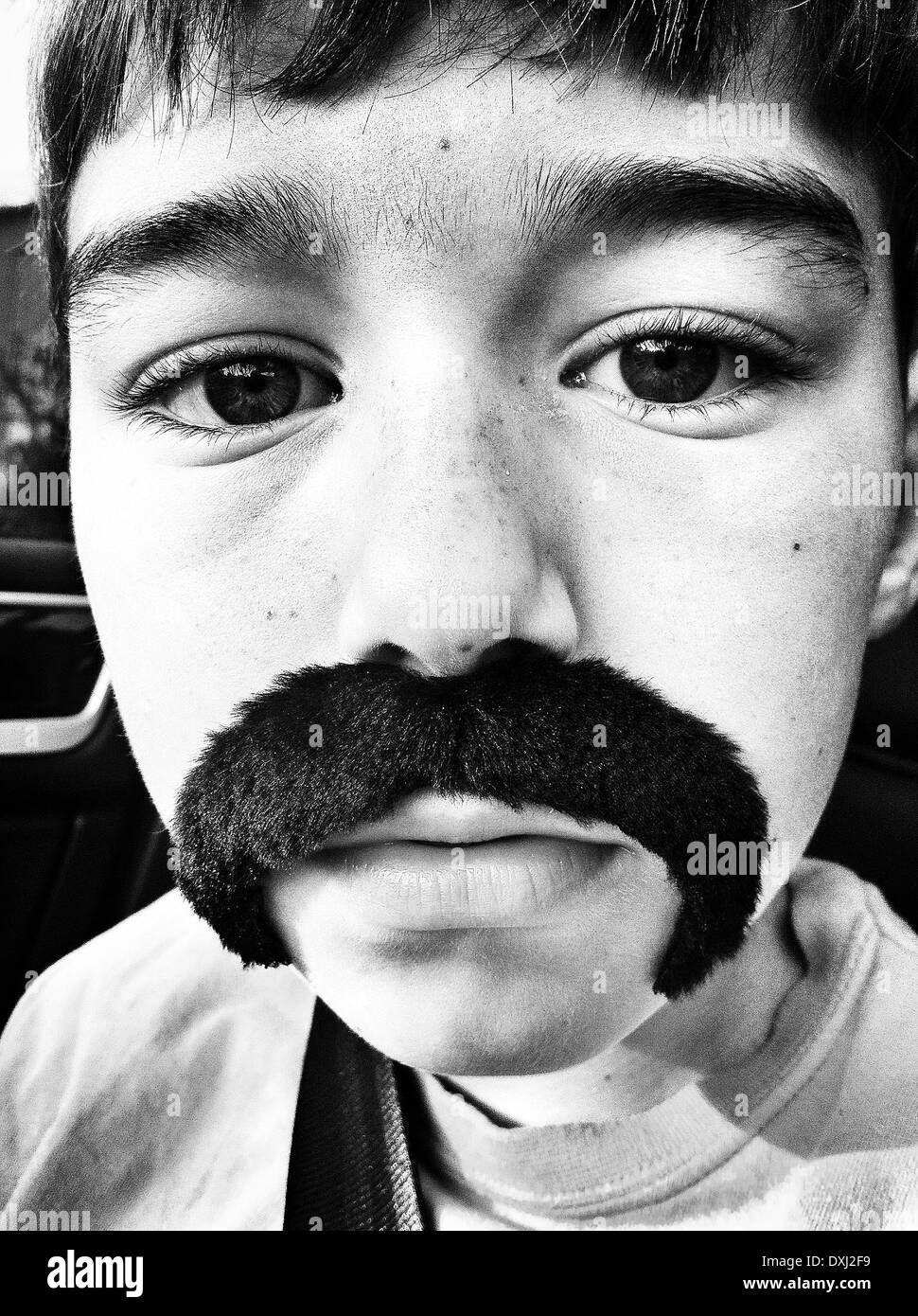 Close up portrait of Caucasian boy wearing fake mustache - Smartphone Captured Stock Image