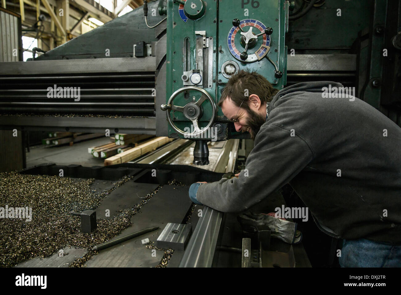Caucasian man working at machinery in metal shop Stock Photo