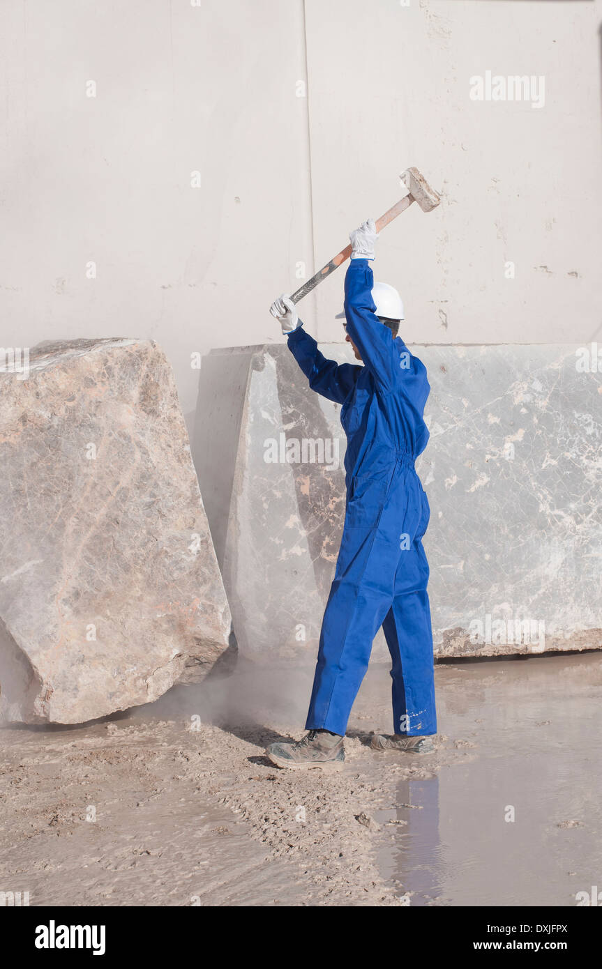 worker attacking marble block with sledgehammer Stock Photo
