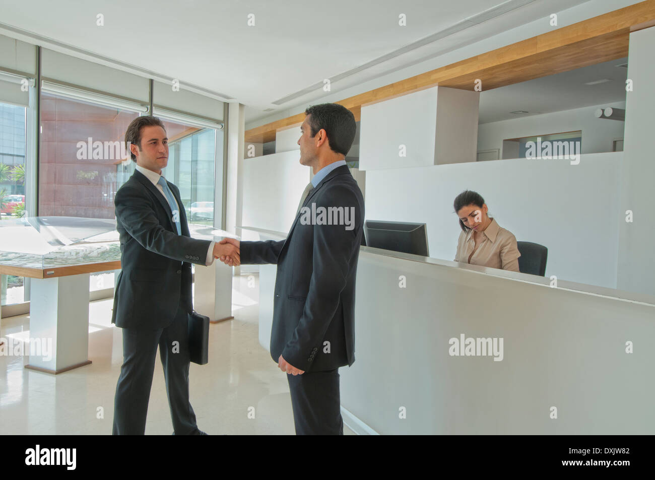 two businessmen shaking hands in office reception Stock Photo