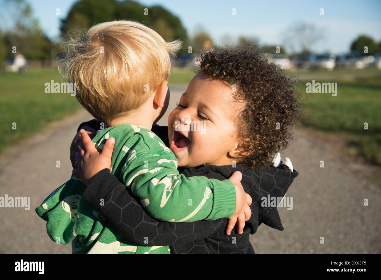 Happy baby boys hugging outdoors Stock Photo