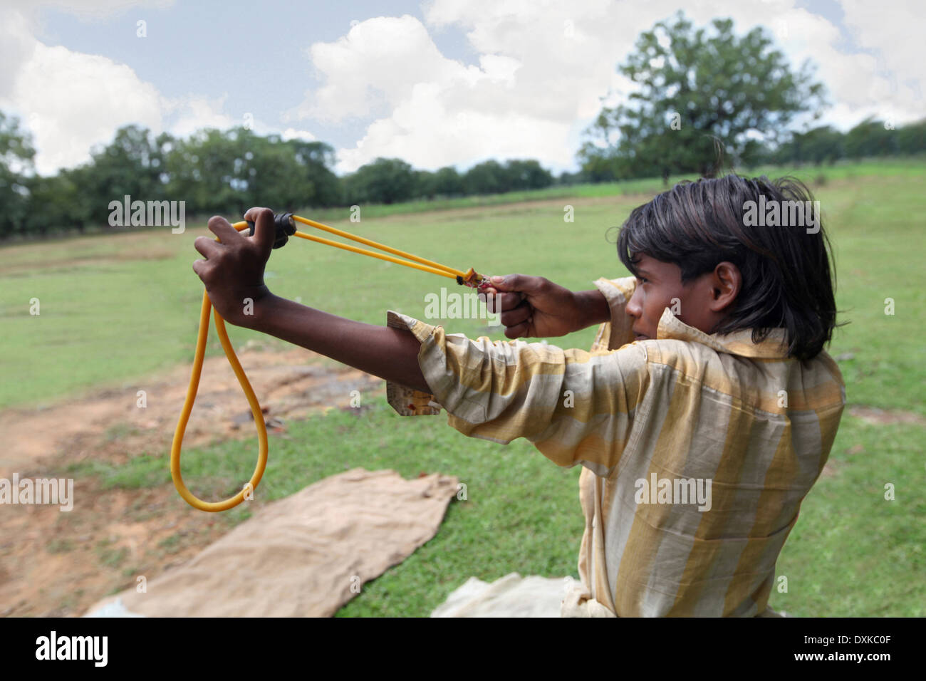 Tribal teenager child with Gulel or slingshot, aiming at the pray. Musahar or Bhuija tribe. Keredari village, Hazaribaug, Jharkh Stock Photo