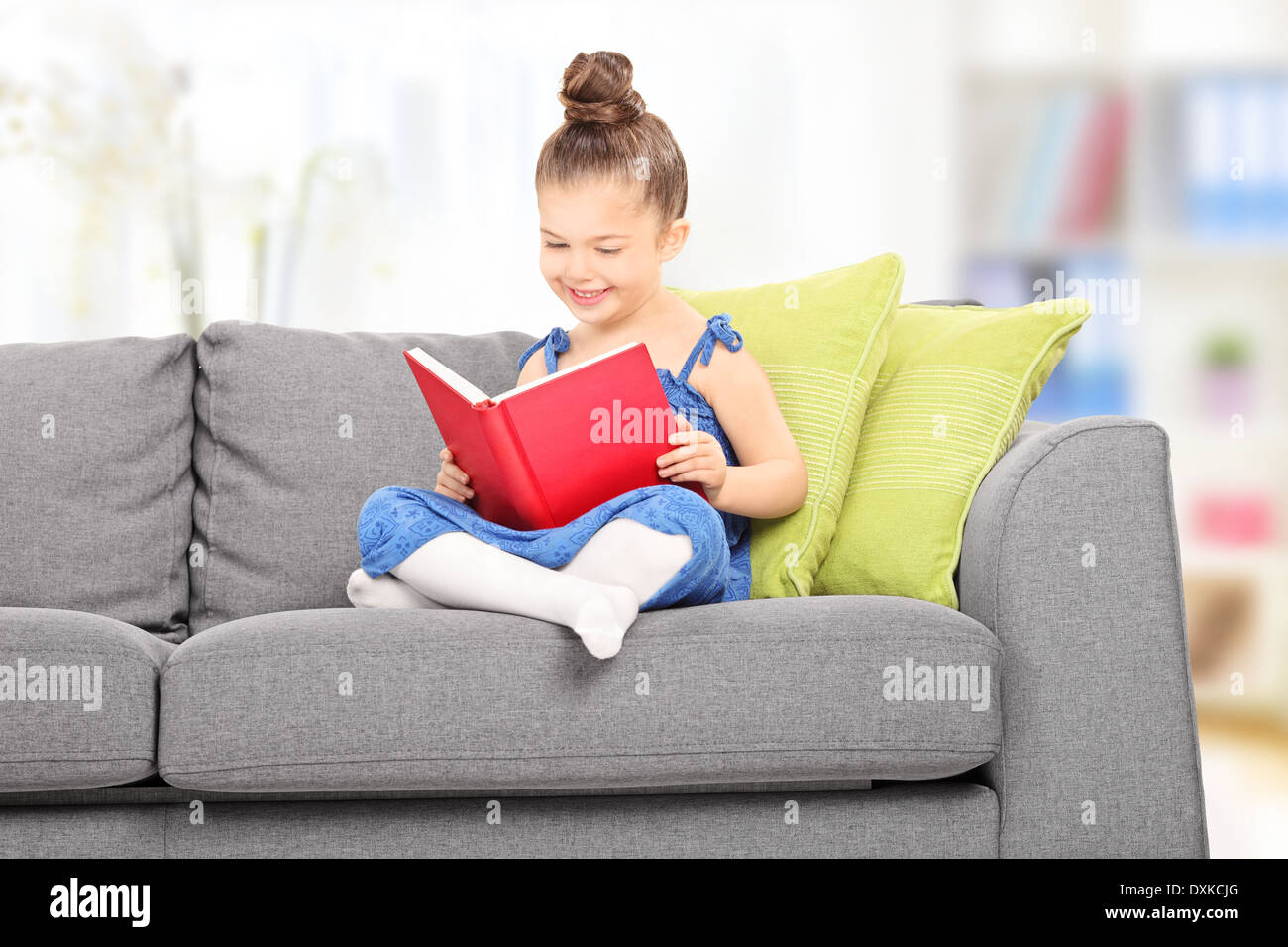 Cute little girl reading a book in the living room at home Stock Photo ...