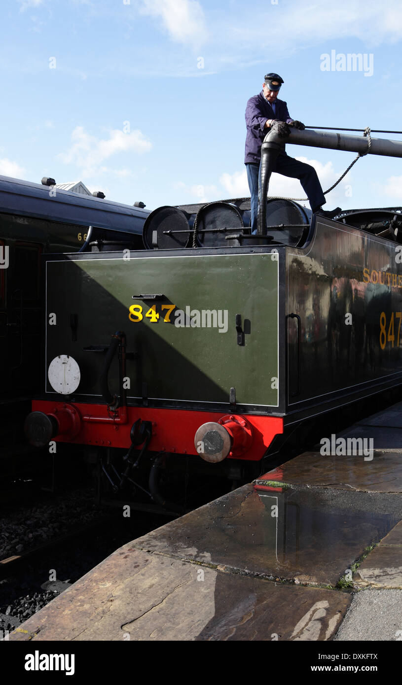 Railway worker filling tender of steam locomotive with water at Sheffield Park station, Bluebell Railway Stock Photo