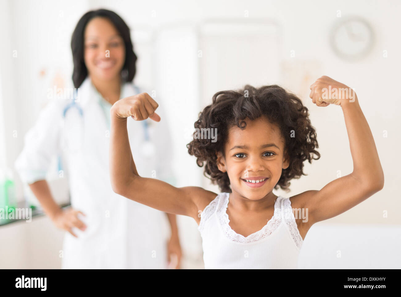 Portrait of African American girl flexing muscles in doctor's office Stock Photo
