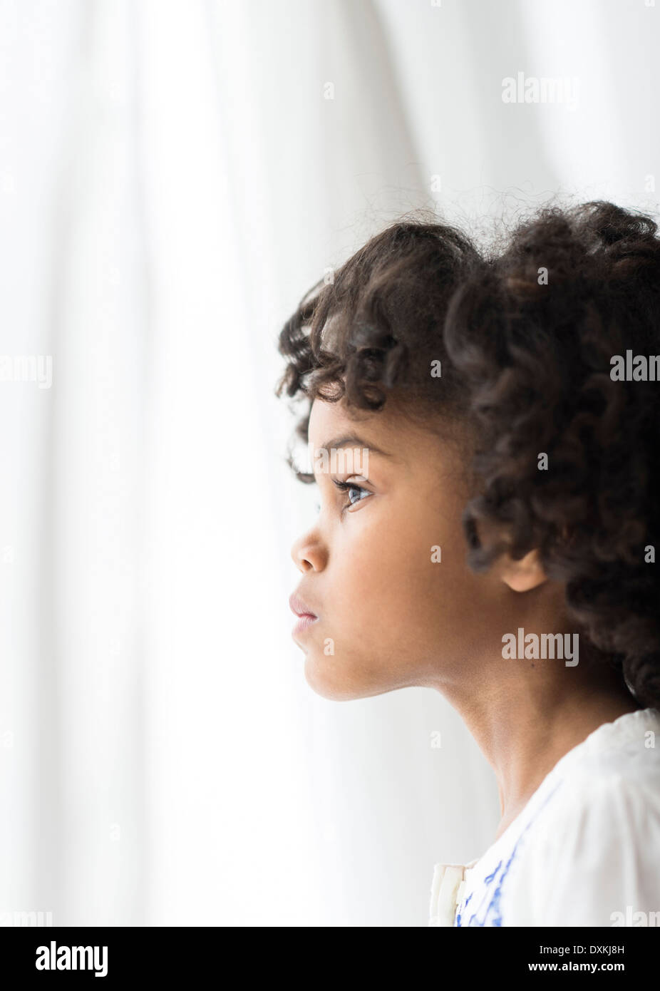 Close up of pensive African American girl looking out window Stock Photo