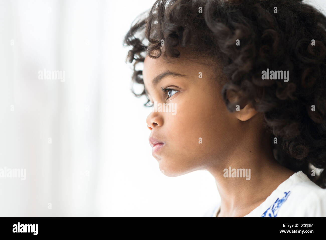 Close up of pensive African American girl looking out window Stock Photo