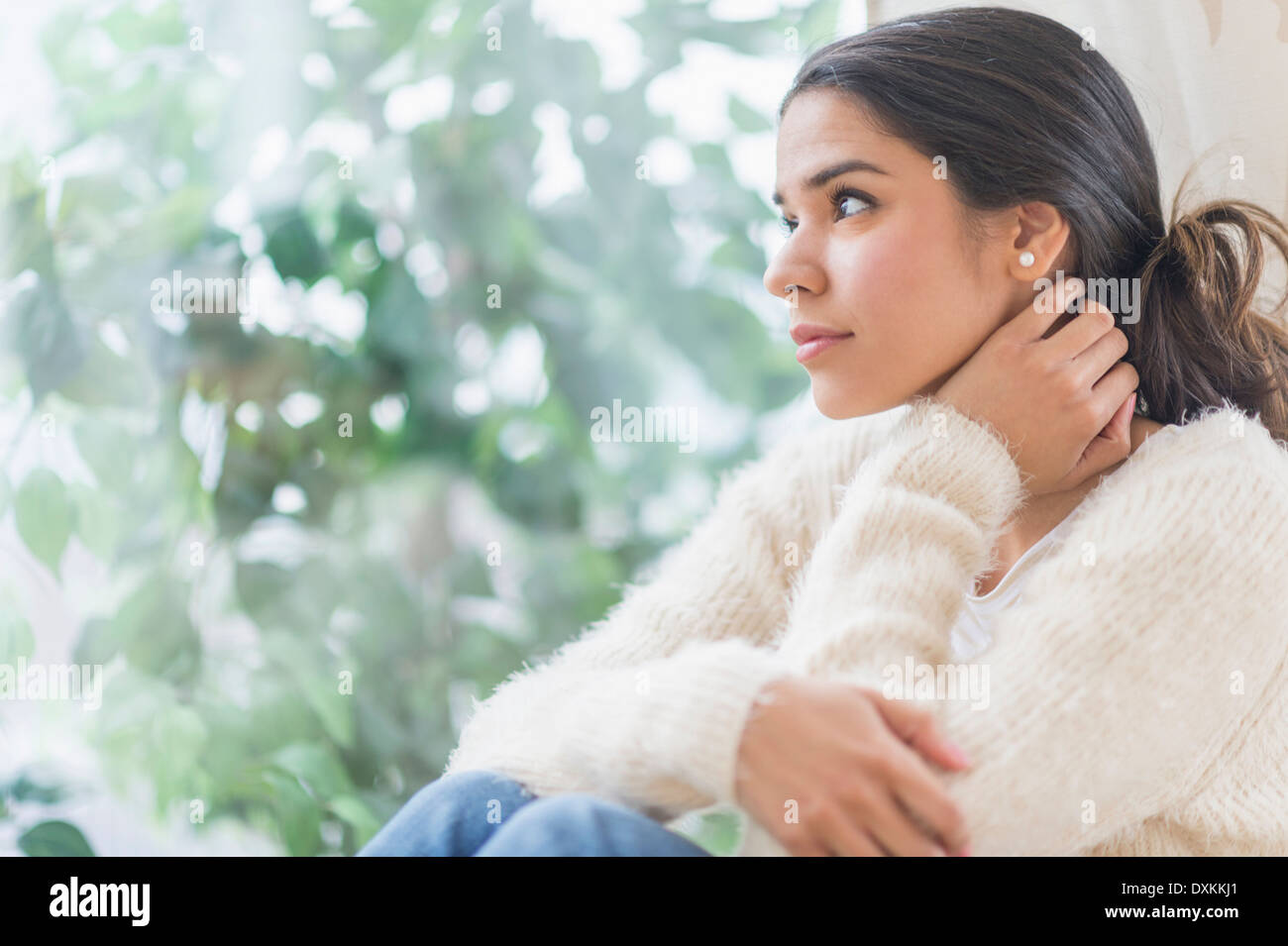 Pensive Hispanic woman looking out window Stock Photo