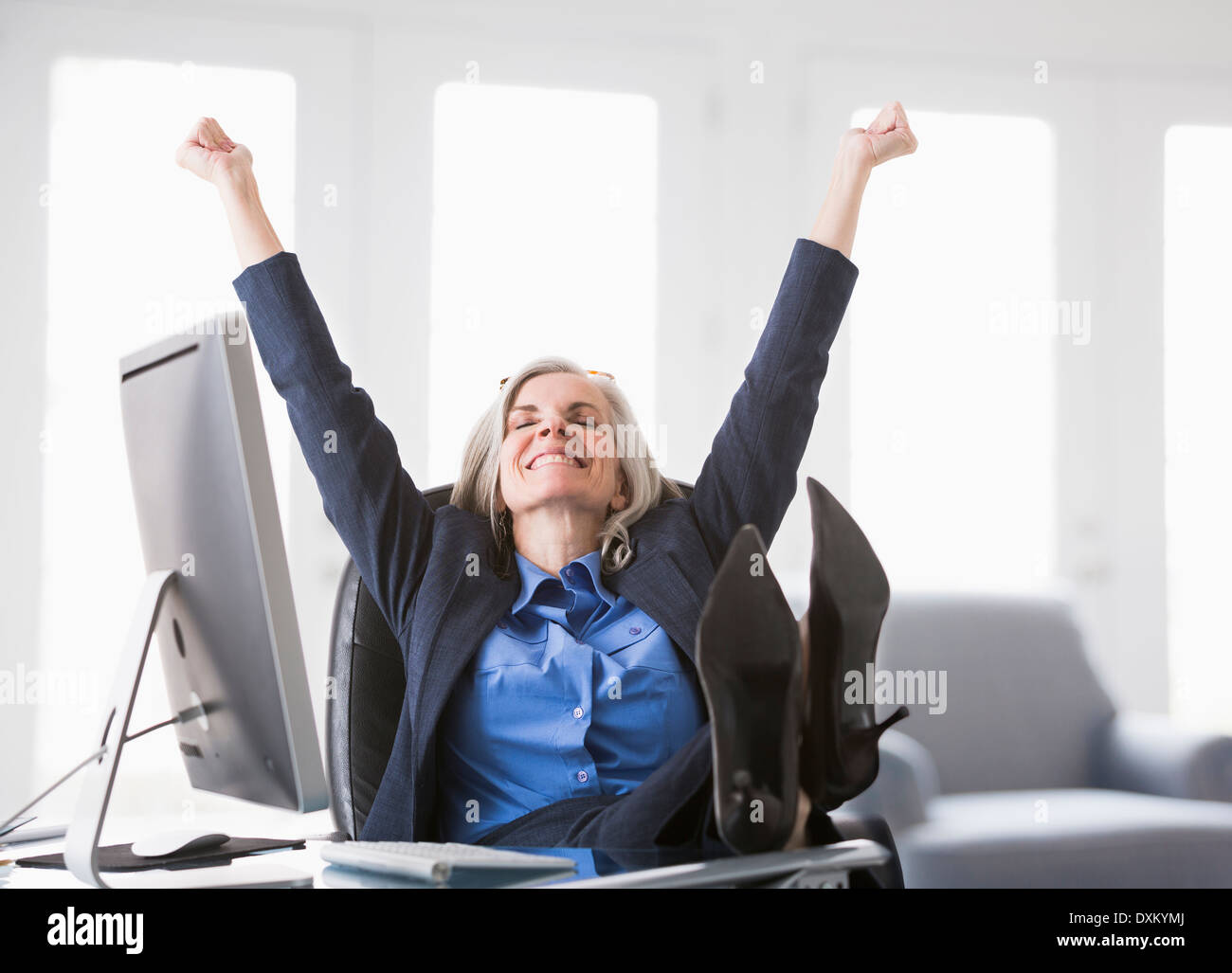 Happy Caucasian businesswoman with feet up on desk Stock Photo