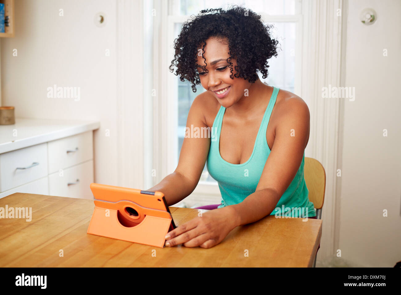 Mixed race woman using digital tablet in kitchen Stock Photo