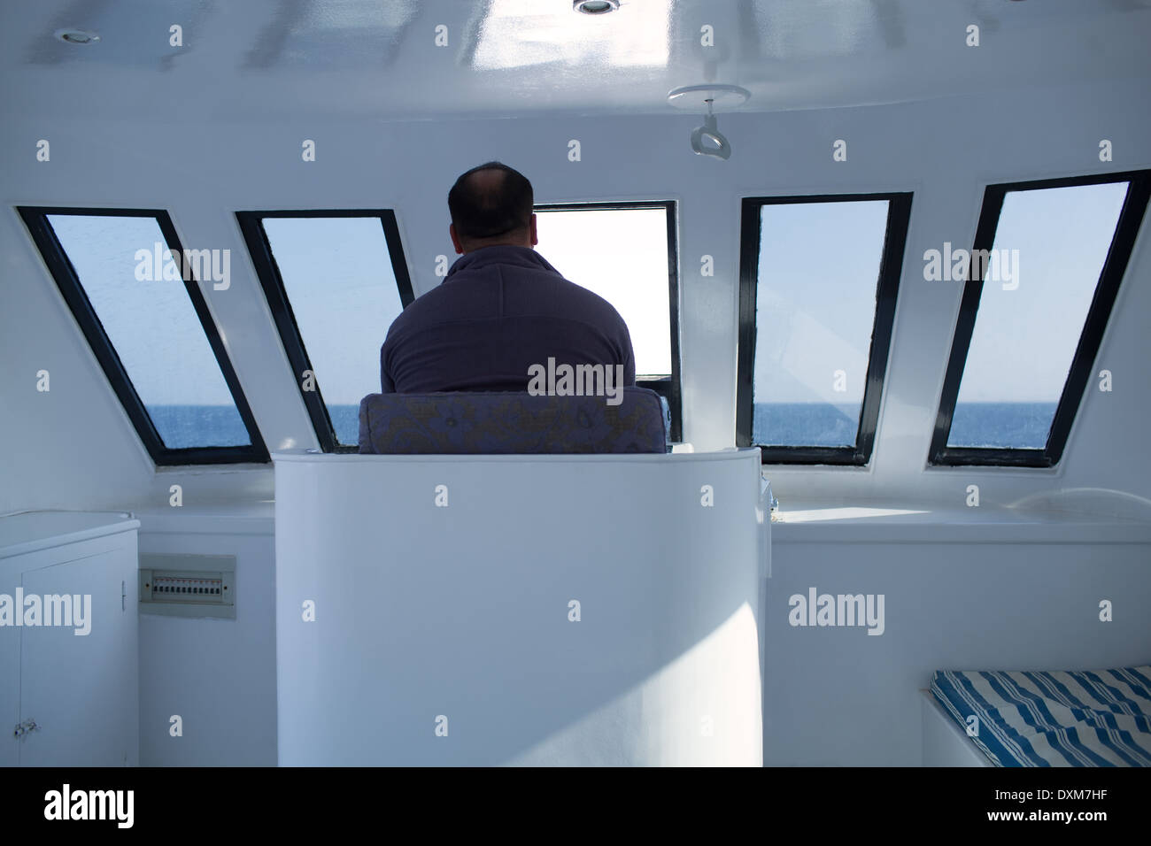 Man Navigating A Boat Sitting In The Captains Chair During A