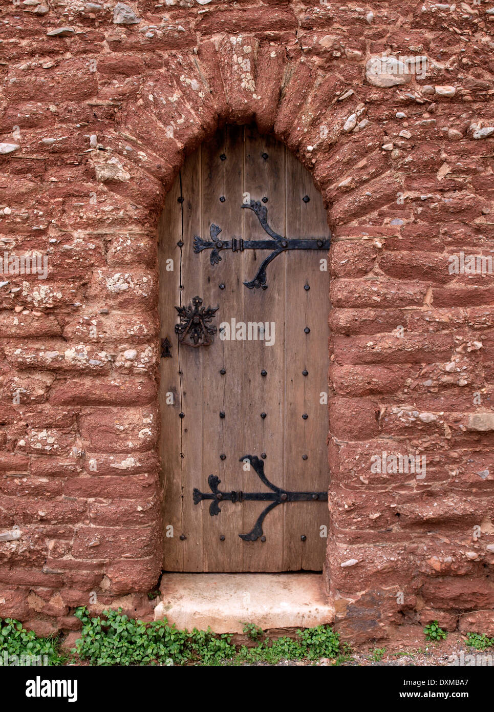 Old wooden arched door through wall Stock Photo