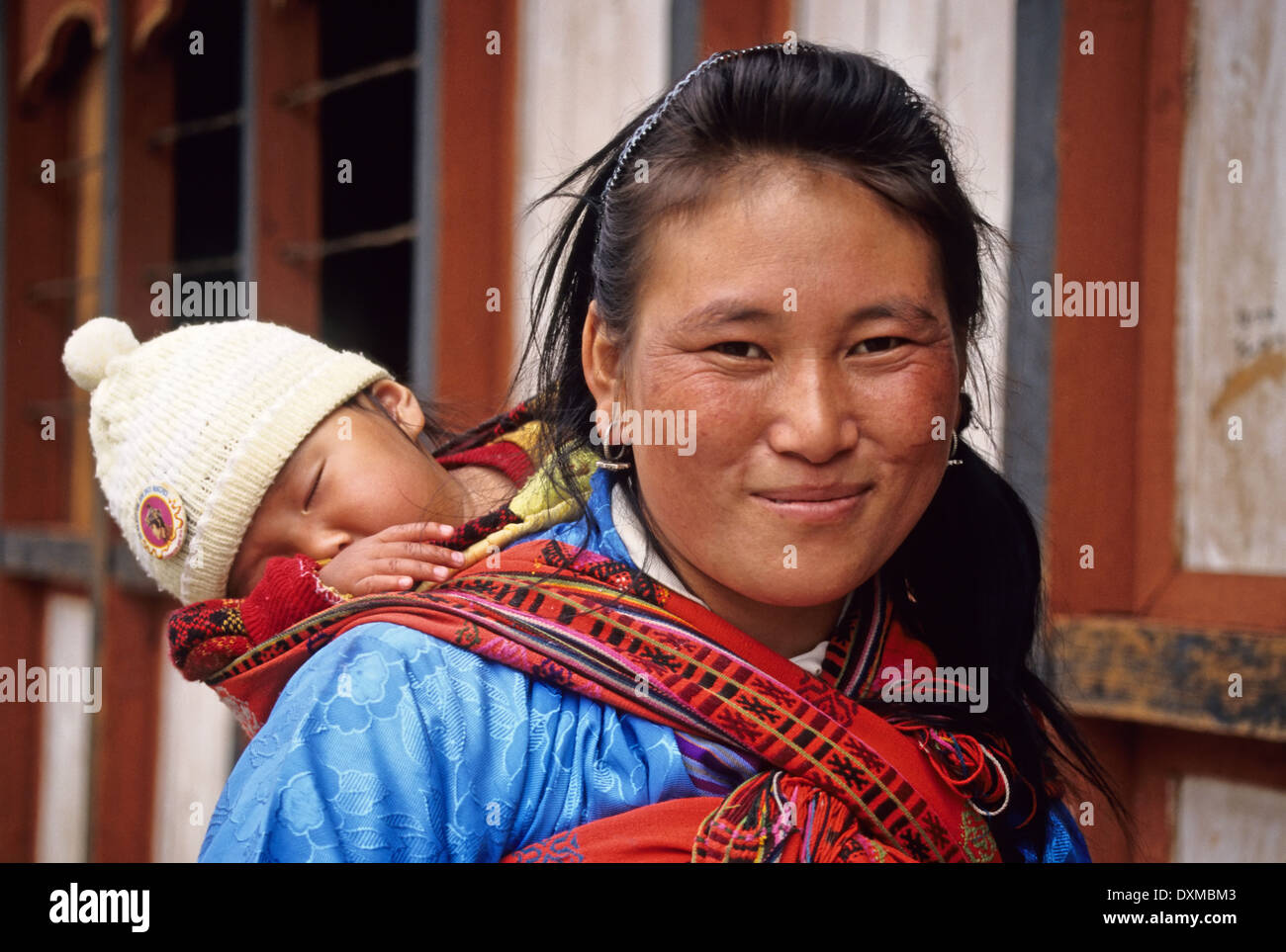 Woman carrying a baby in a multi-coloured sling, Jakar, Bhutan Stock Photo