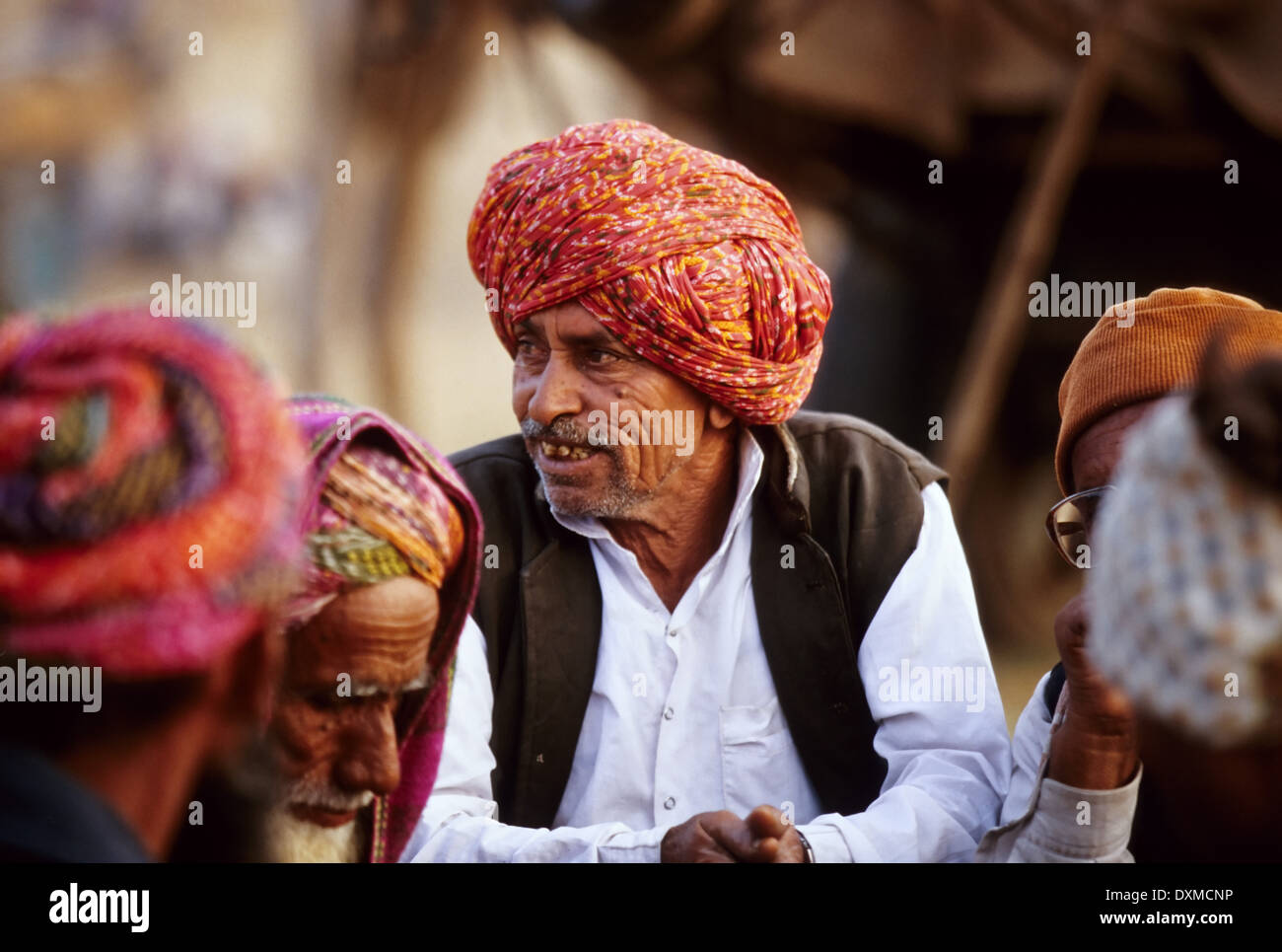 Indian man wearing a red and orange turban in a group of men Stock Photo