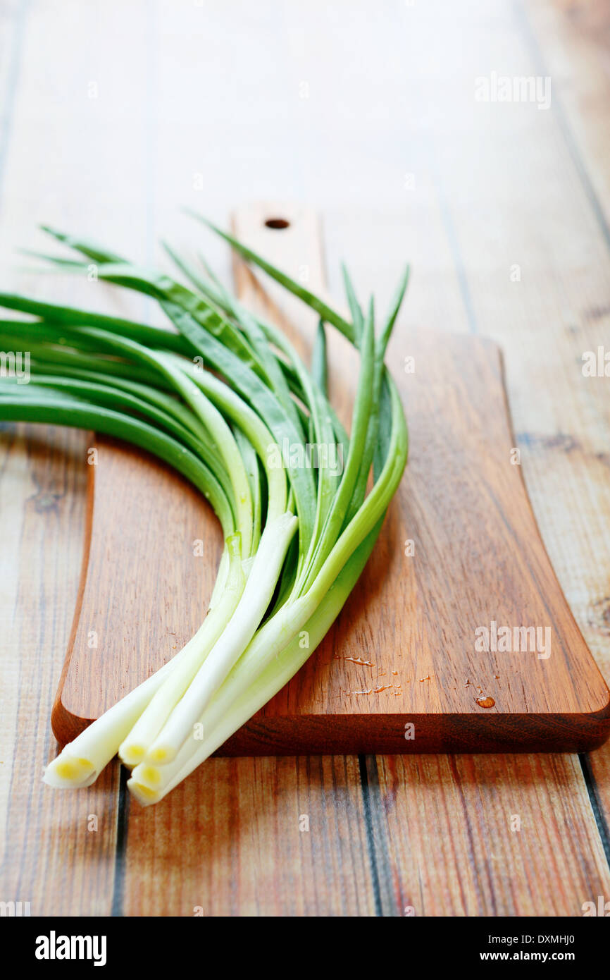 bunch of green onions on a cutting board, food closeup Stock Photo
