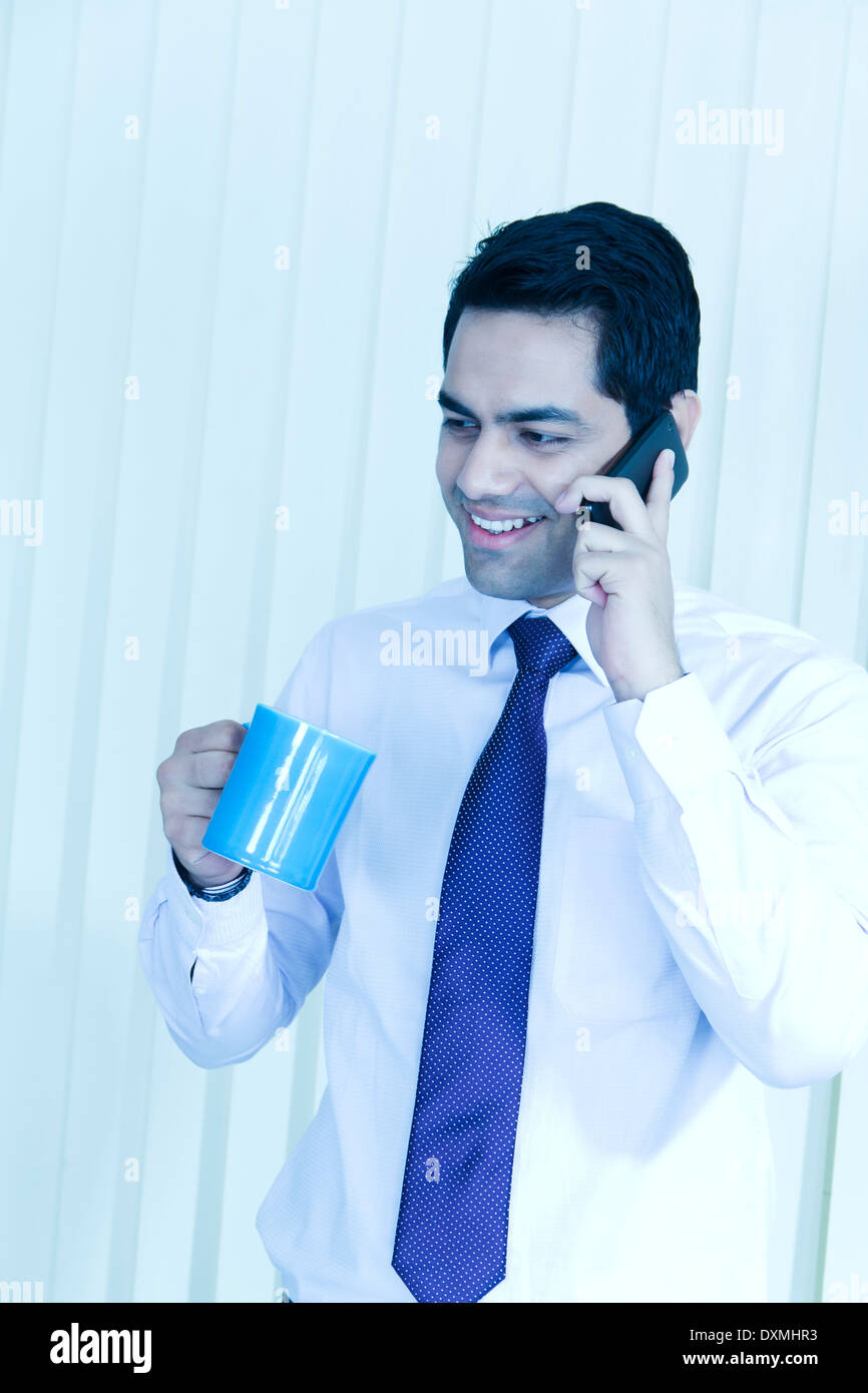 1 Indian Businessman Drinking Tea and Talking with Mobile Stock Photo