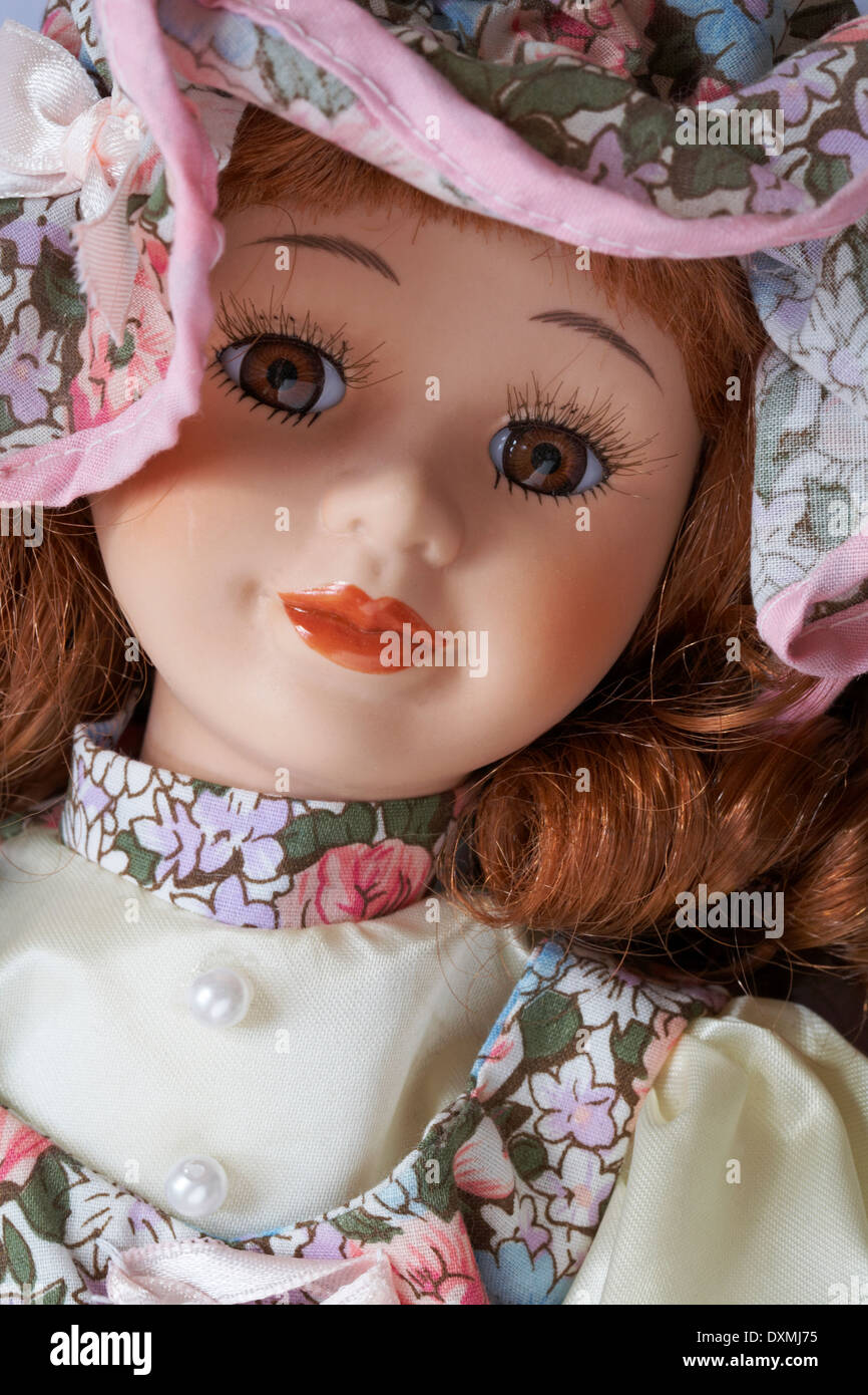 Close up of face of porcelain doll with ringlets wearing a hat Stock Photo
