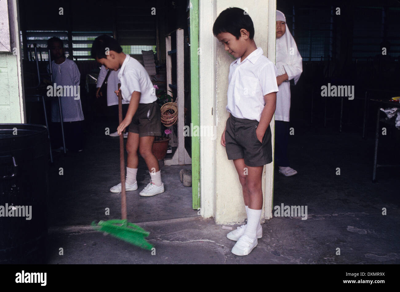 Sweeping up. Schoolchildren at school in Brunei, South East Asia Stock Photo