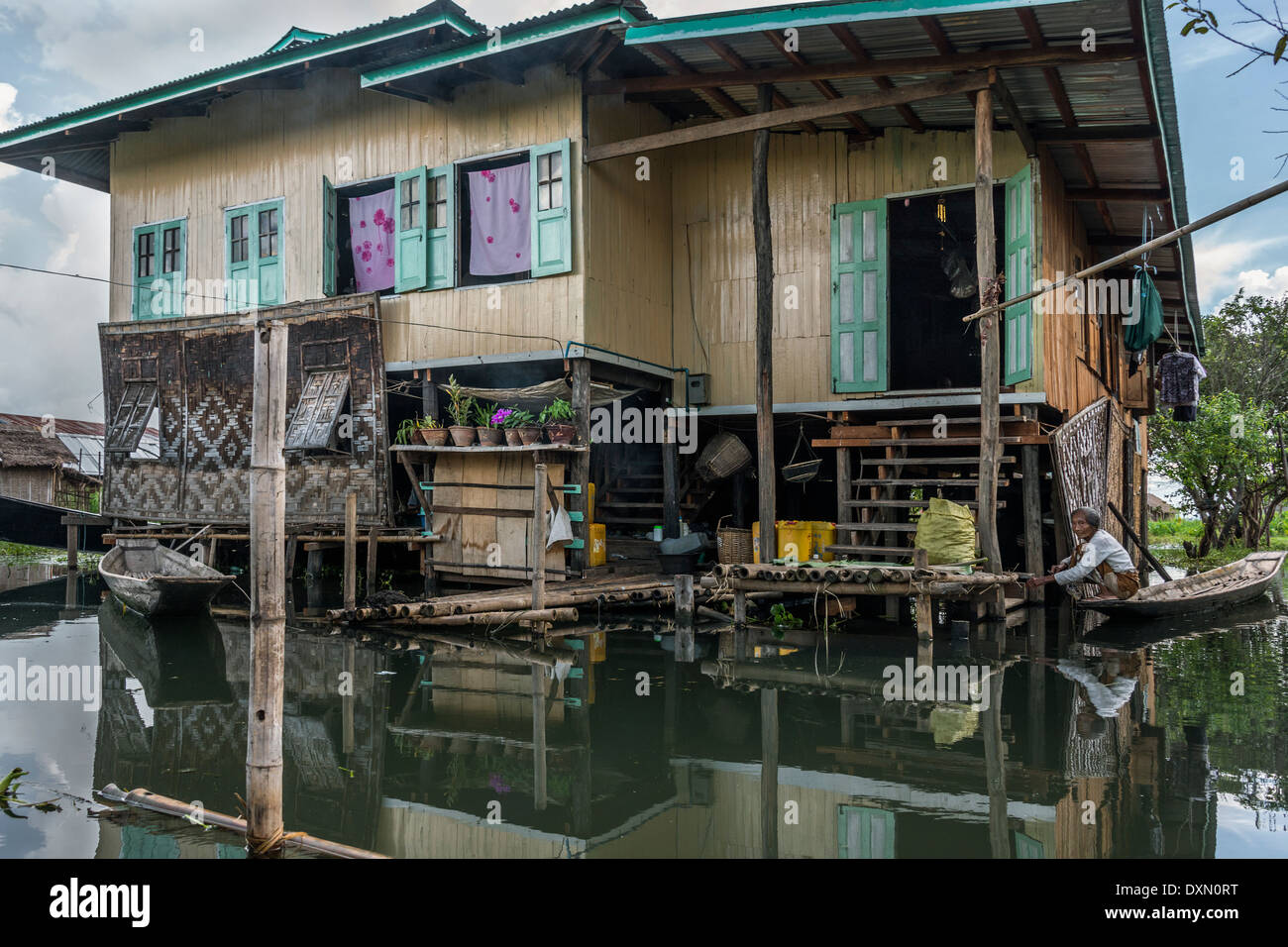 Woman tying her canoe up to her house, Inle Lake, Myanmar Stock Photo