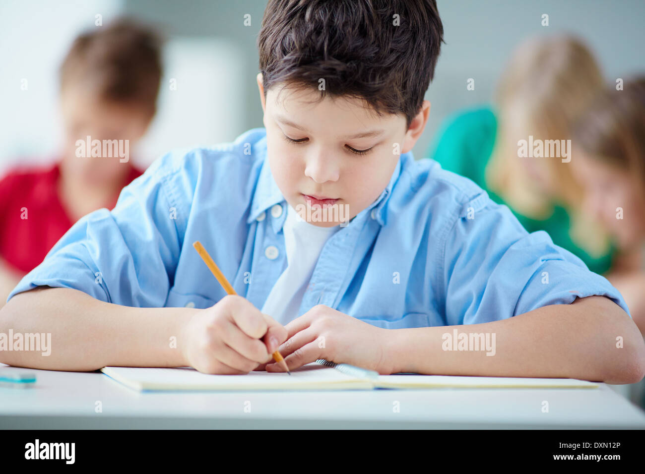 Portrait of cute schoolboy drawing at workplace during lesson Stock ...