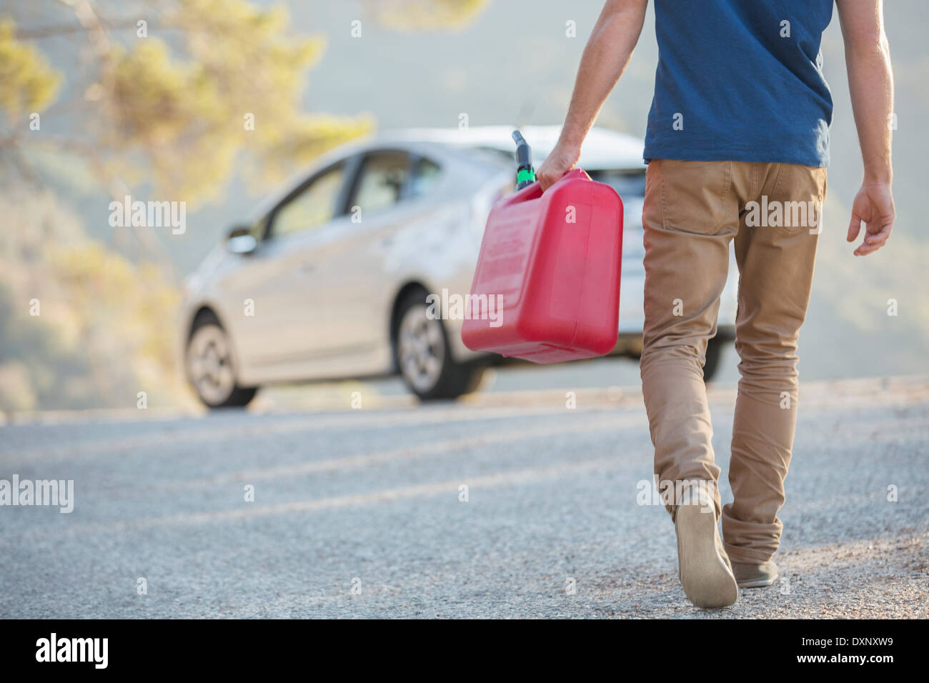 Man carrying gas can to car at roadside Stock Photo