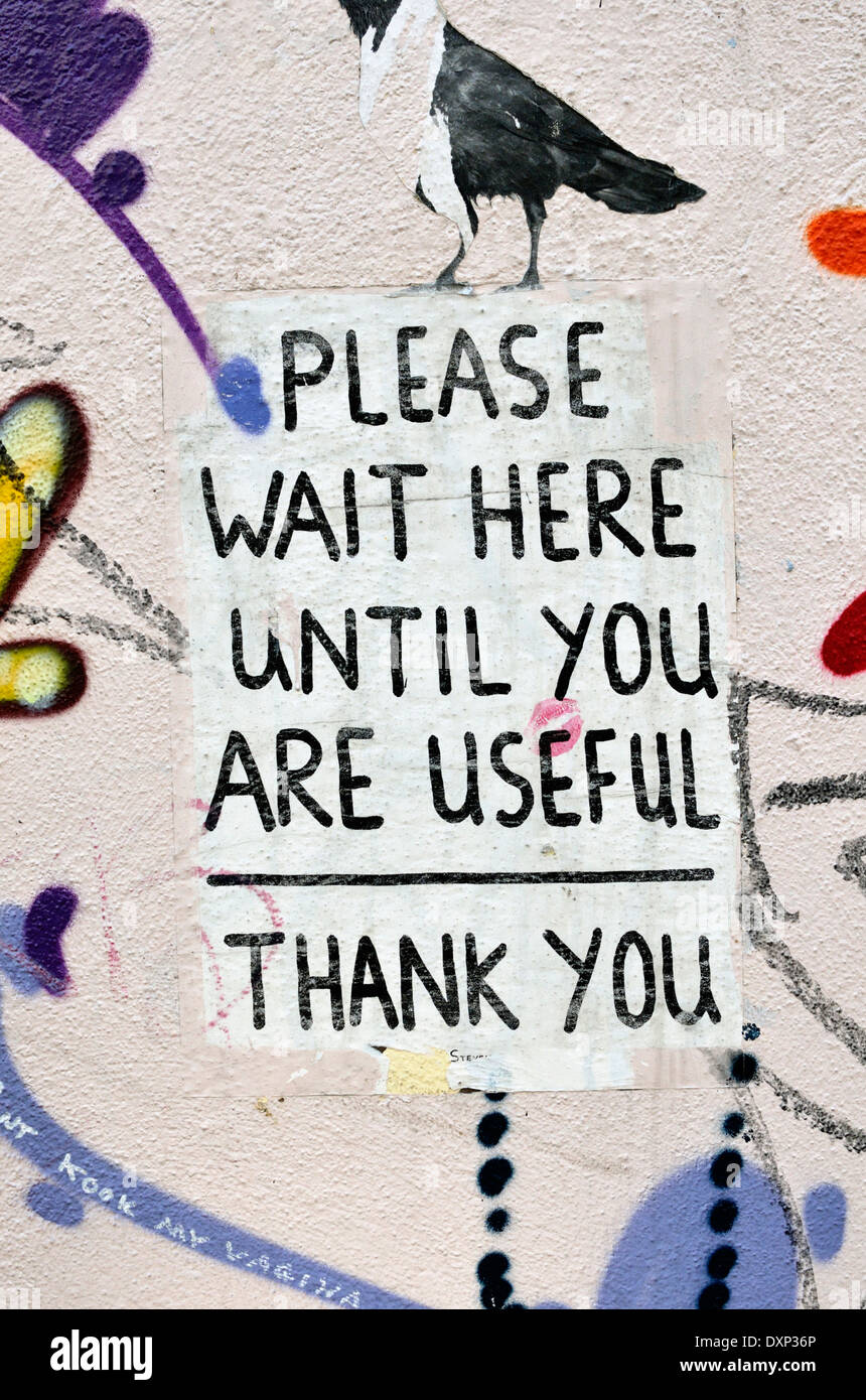 ’Please wait here until you are useful’ sign painted on a wall, Shoreditch, London, UK. Stock Photo