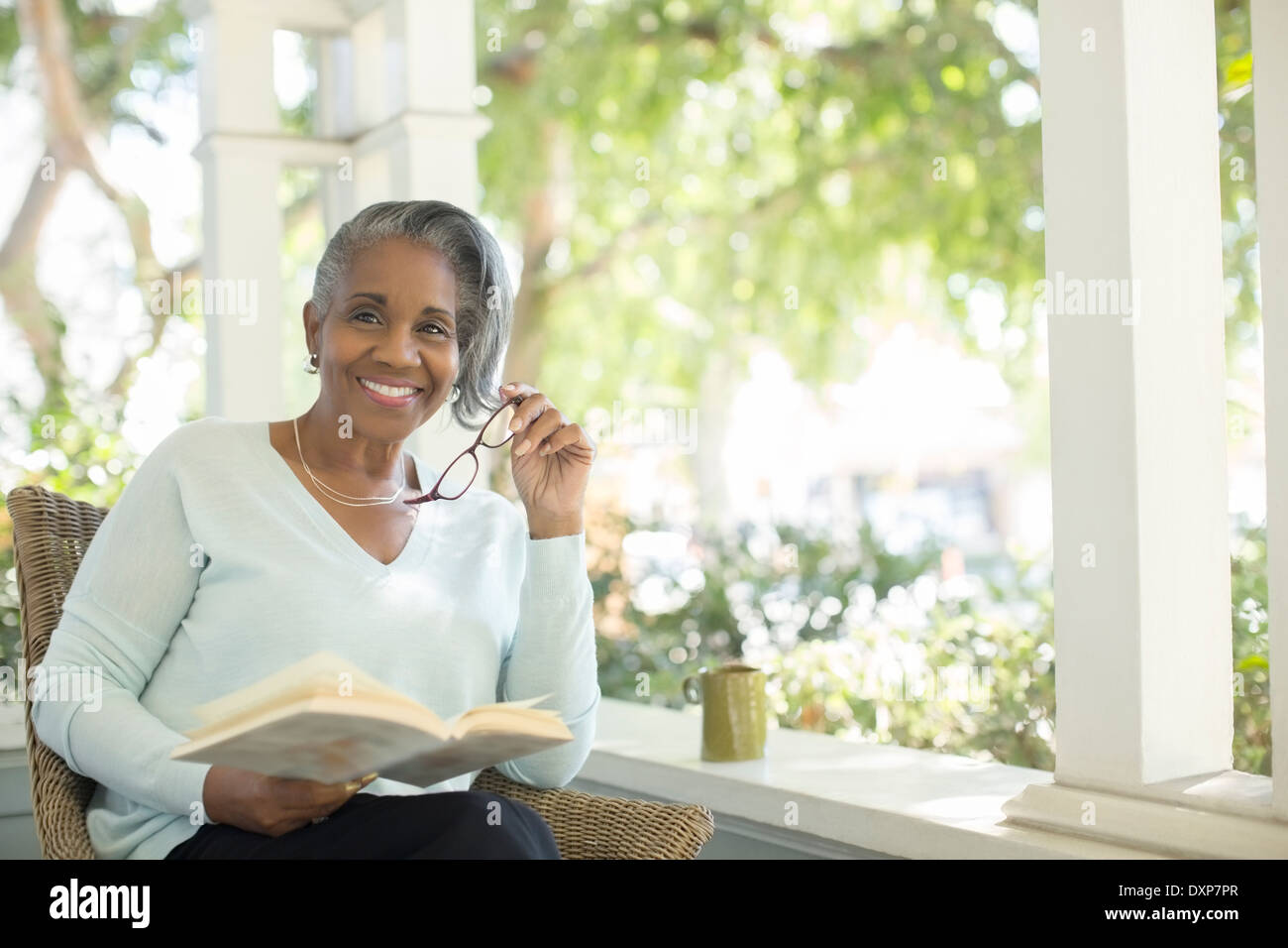 Portrait of smiling senior woman reading book on porch Stock Photo - Alamy