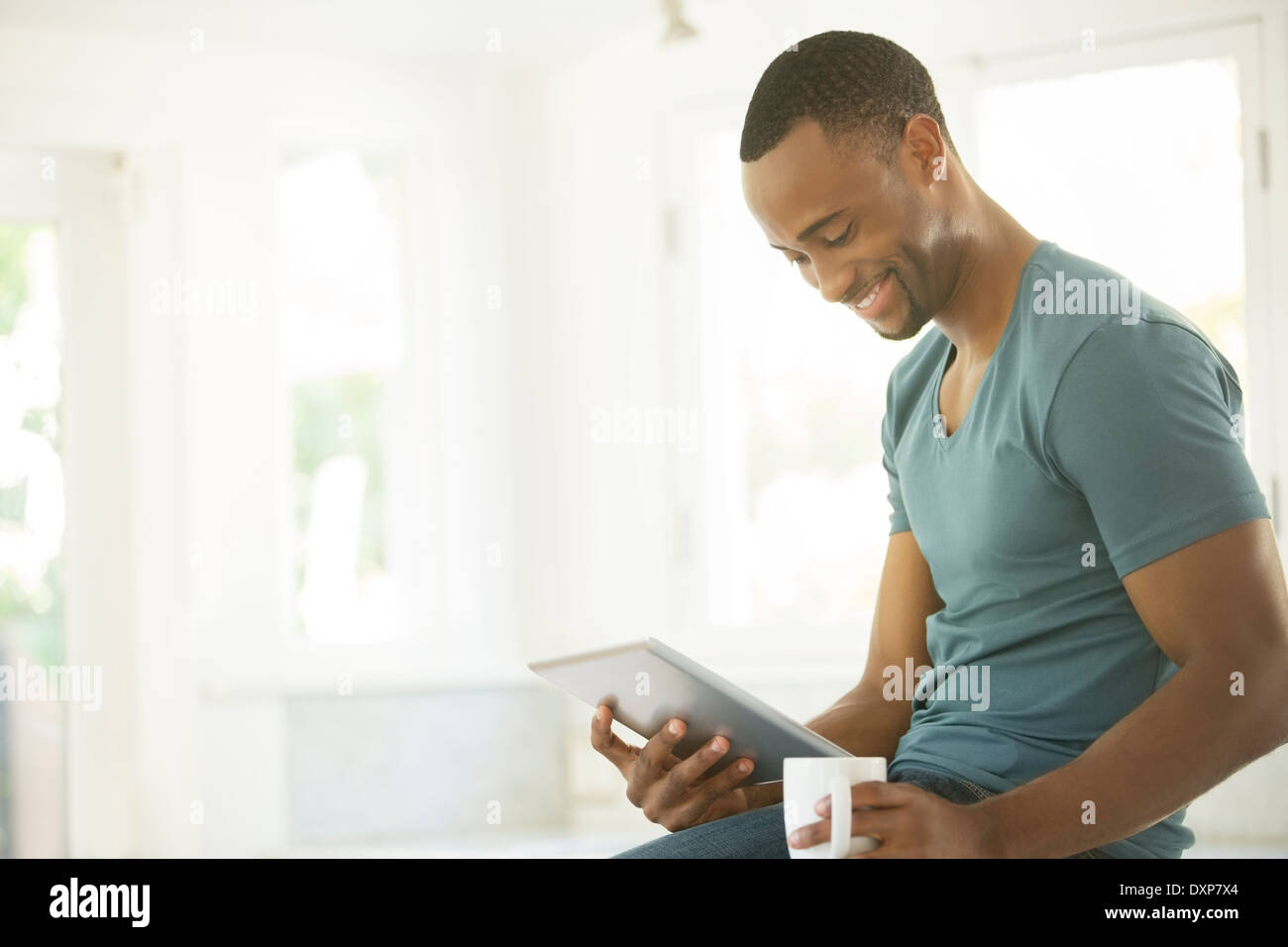 Smiling man drinking coffee and using digital tablet Stock Photo