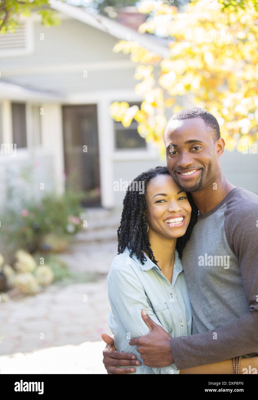 Portrait of smiling couple hugging outside house Stock Photo