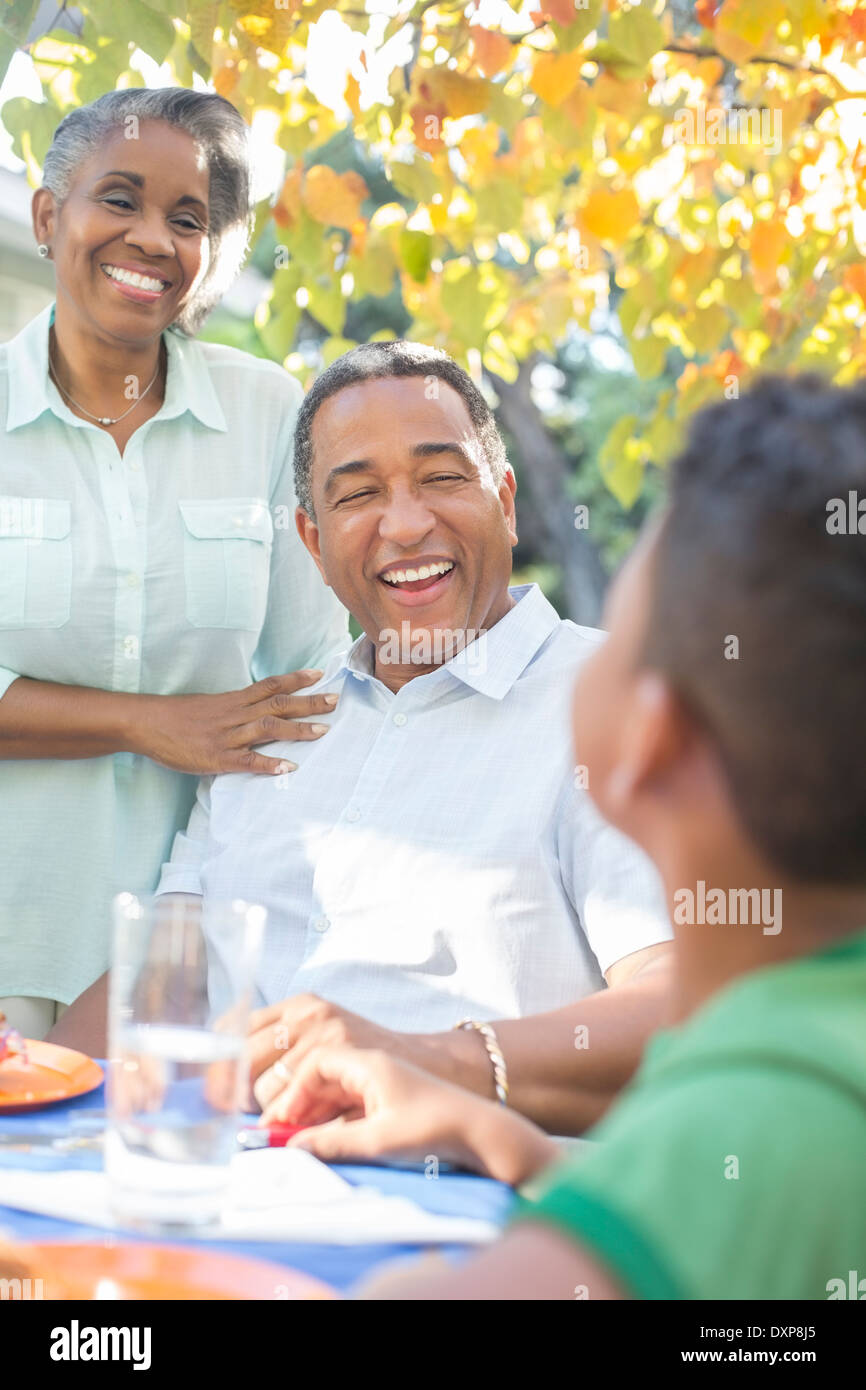 Grandparents and grandson laughing at patio table Stock Photo