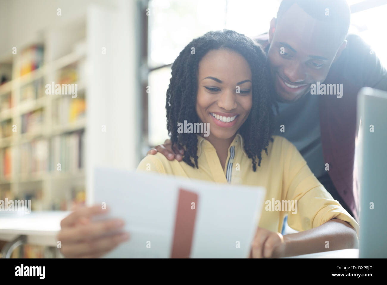 Happy couple reading paperwork at laptop Stock Photo