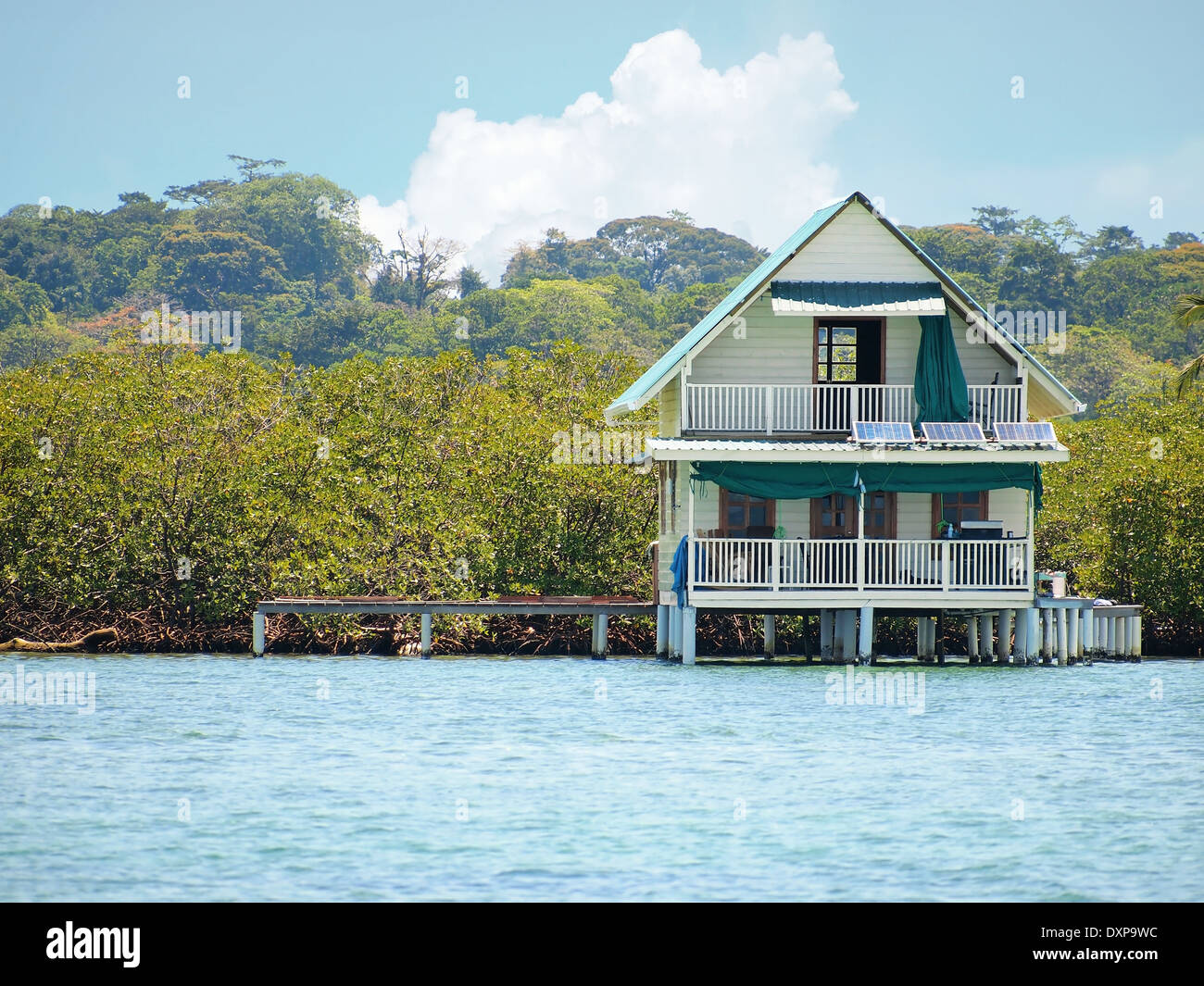 House on stilts over water with solar panels and dense tropical vegetation in background, Bocas del Toro, Caribbean sea, Panama Stock Photo