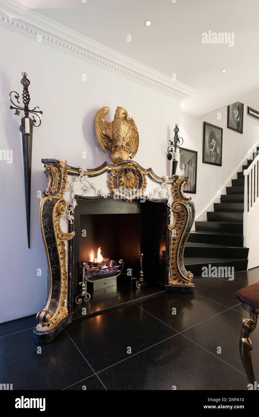 Gilt empire style fireplace by Nicholas Haslam in hallway with black floor tiles Stock Photo